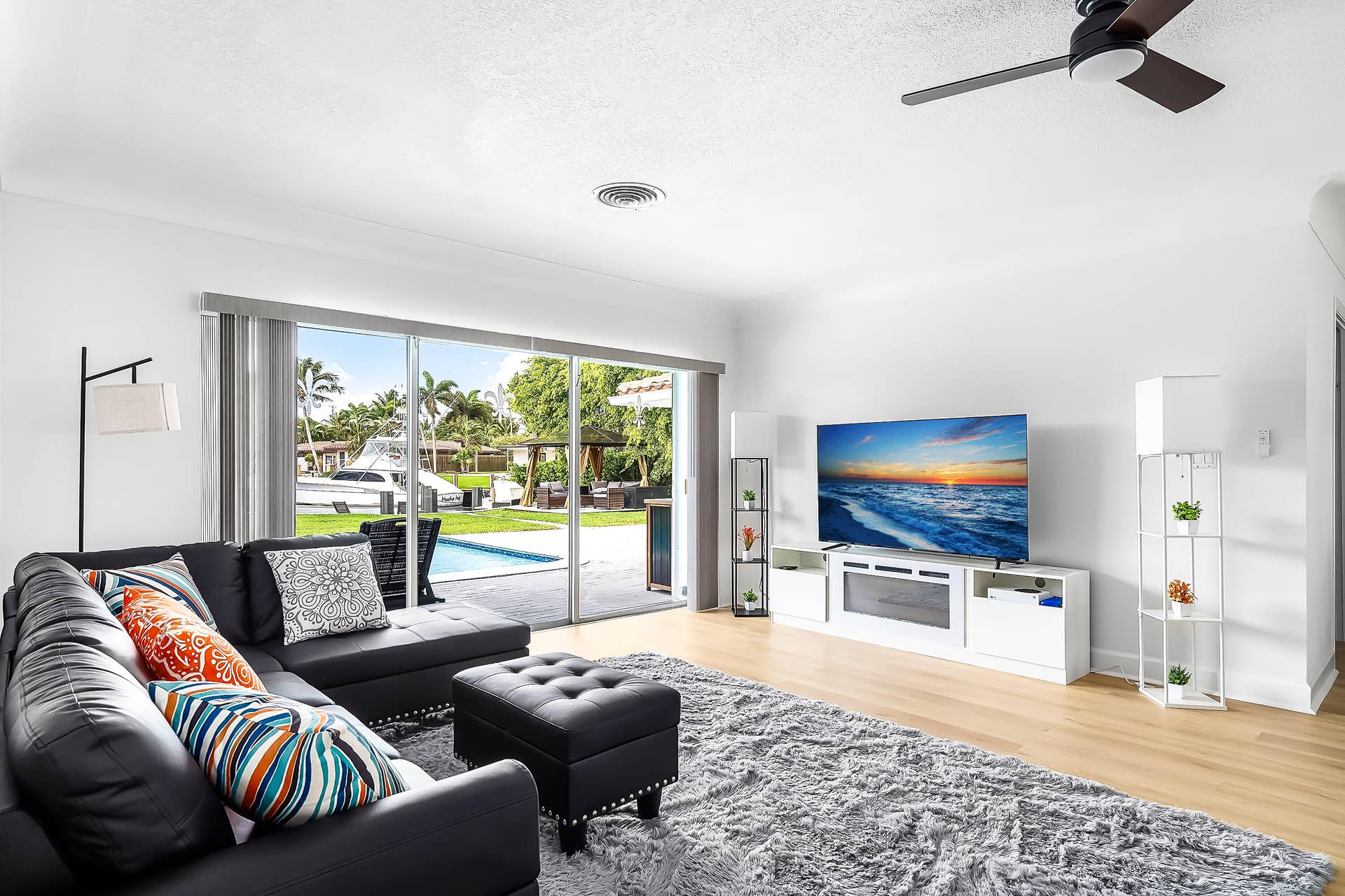 1250 SE 10TH Street, Deerfield Beach, Deerfield Beach, FL 33441 Living area featuring wood-finish flooring, a contemporary ceiling fan, and sliding glass doors opening to a private pool area