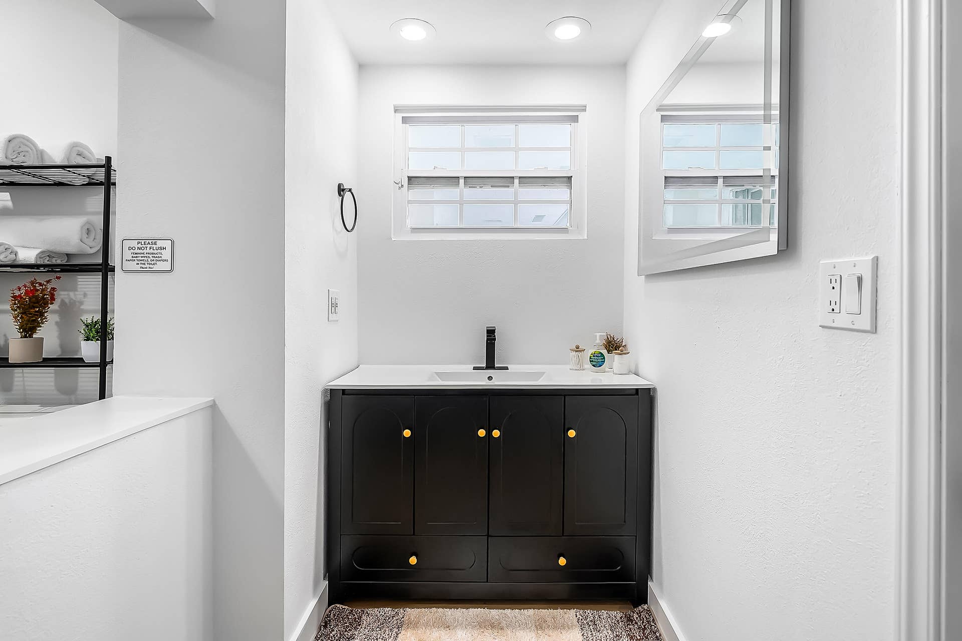1250 SE 10TH Street, Deerfield Beach, Deerfield Beach, FL 33441 Modern bathroom vanity featuring a black cabinet with gold-toned hardware, an integrated white sink, and a contrasting white countertop