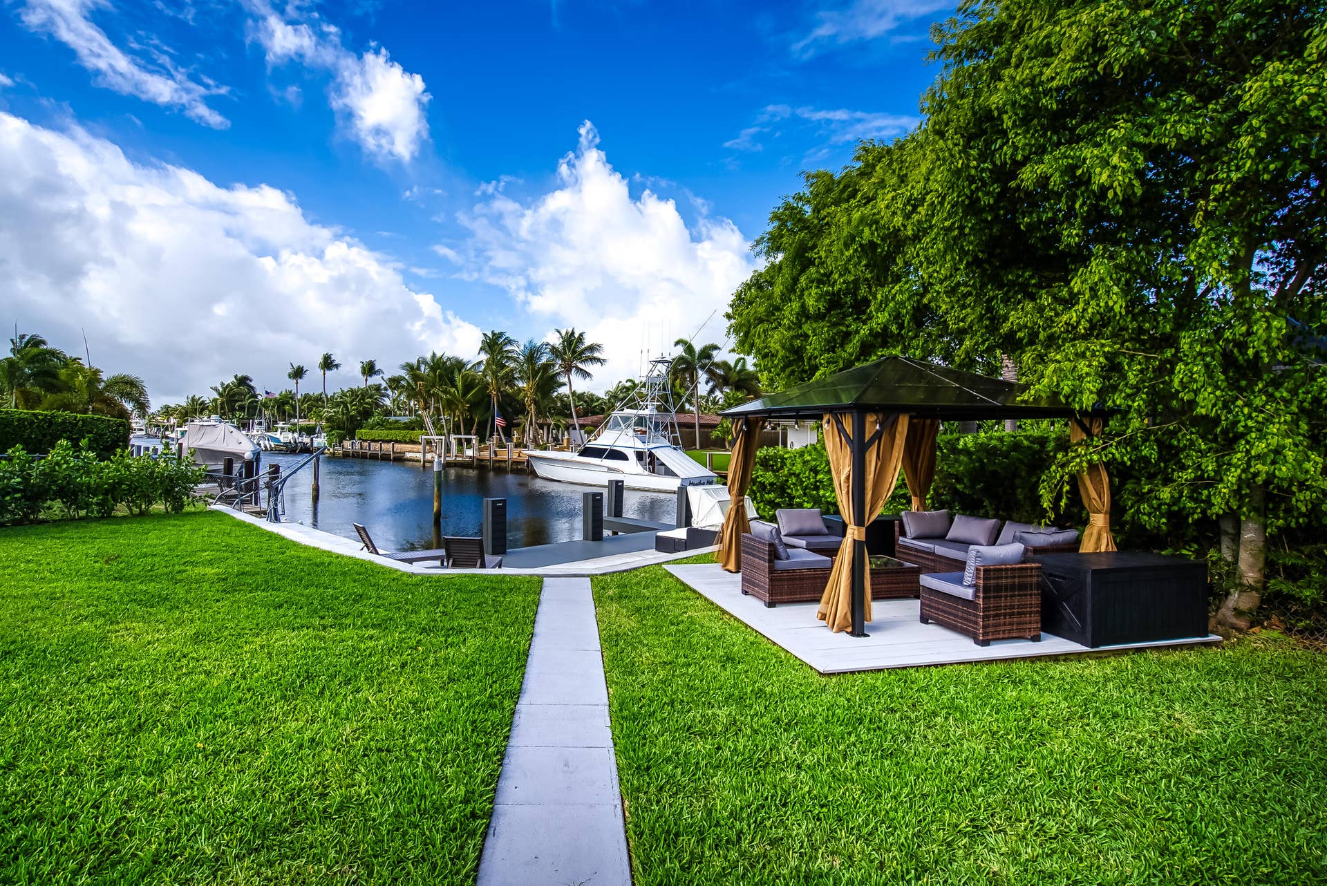 1250 SE 10TH Street, Deerfield Beach, Deerfield Beach, FL 33441 Waterside patio with a paved seating area, mature trees, manicured lawn, and dock access