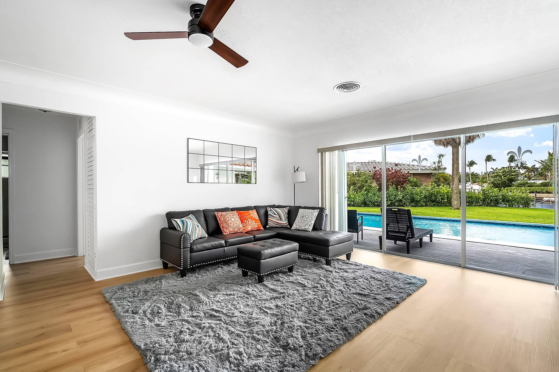 1250 SE 10TH Street, Deerfield Beach, Deerfield Beach, FL 33441 Bright living space featuring expansive sliding glass doors, light wood-finish flooring, and a contemporary ceiling fan