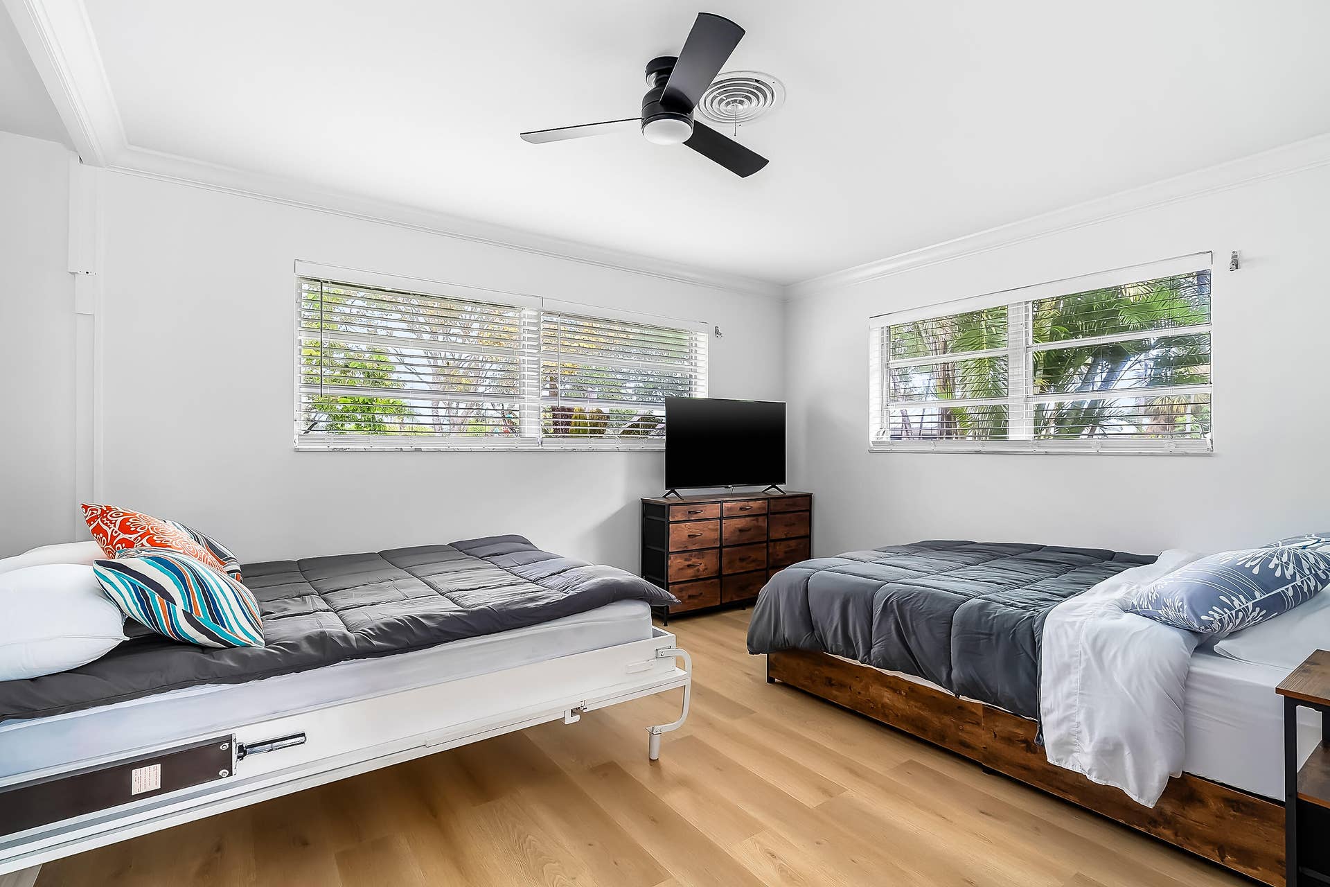 1250 SE 10TH Street, Deerfield Beach, Deerfield Beach, FL 33441 Bright room featuring wood-finish flooring, two large windows with blinds, a black ceiling fan, and crown molding