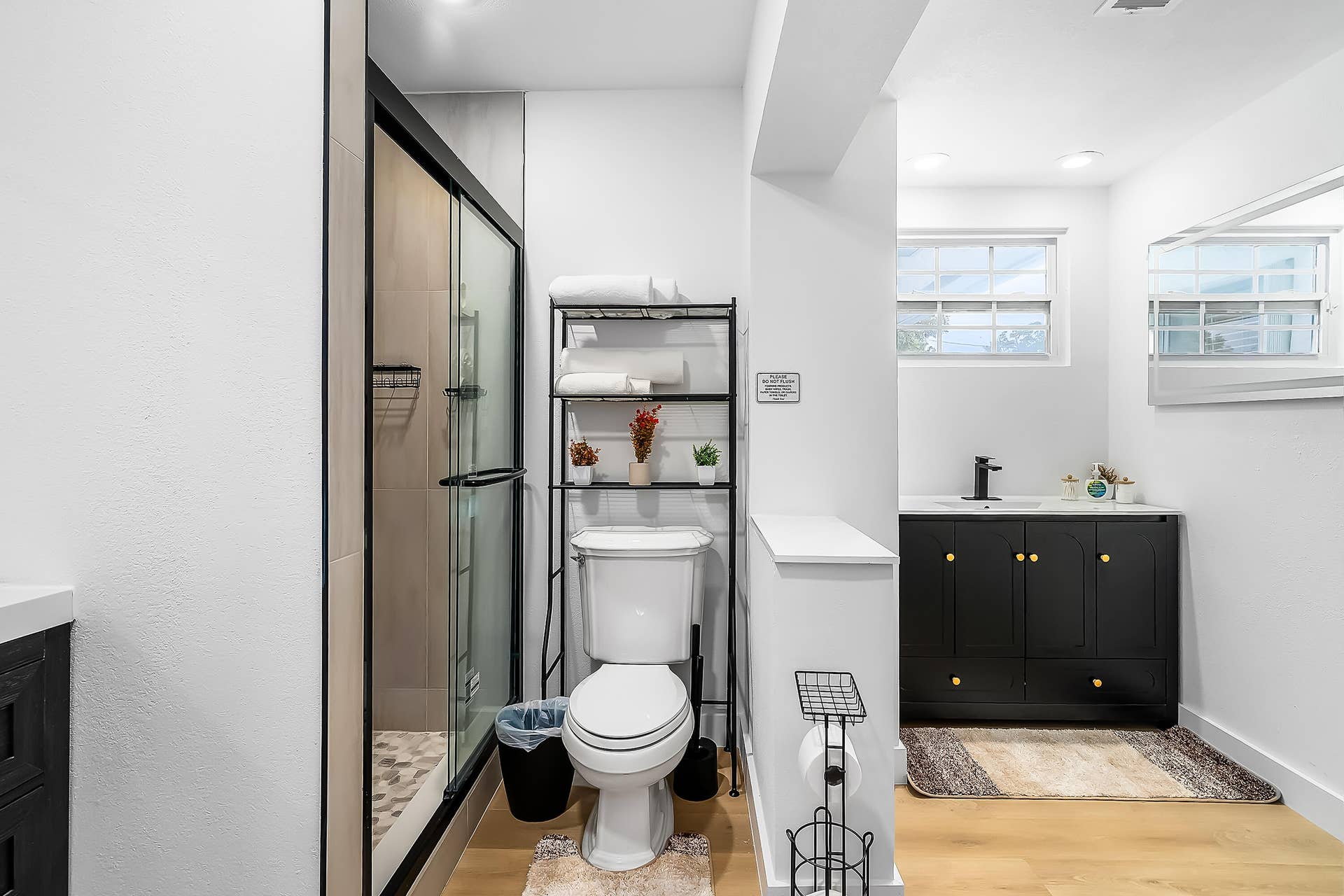 1250 SE 10TH Street, Deerfield Beach, Deerfield Beach, FL 33441 Shower with black-framed glass enclosure, toilet, and black vanity with gold-tone hardware