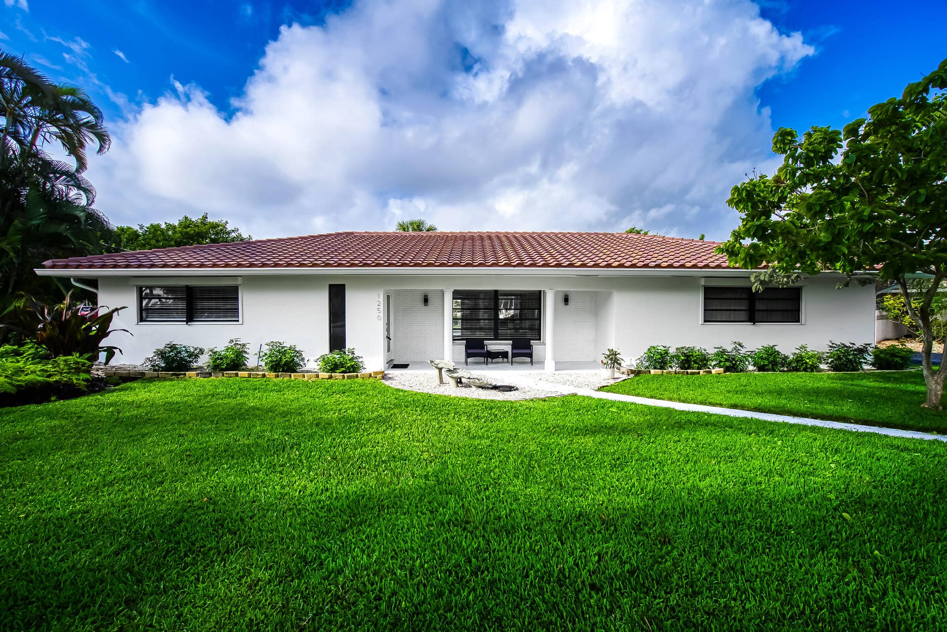 1250 SE 10TH Street, Deerfield Beach, Deerfield Beach, FL 33441 White stucco exterior with a terra cotta tile roof, featuring a covered entry porch with seating