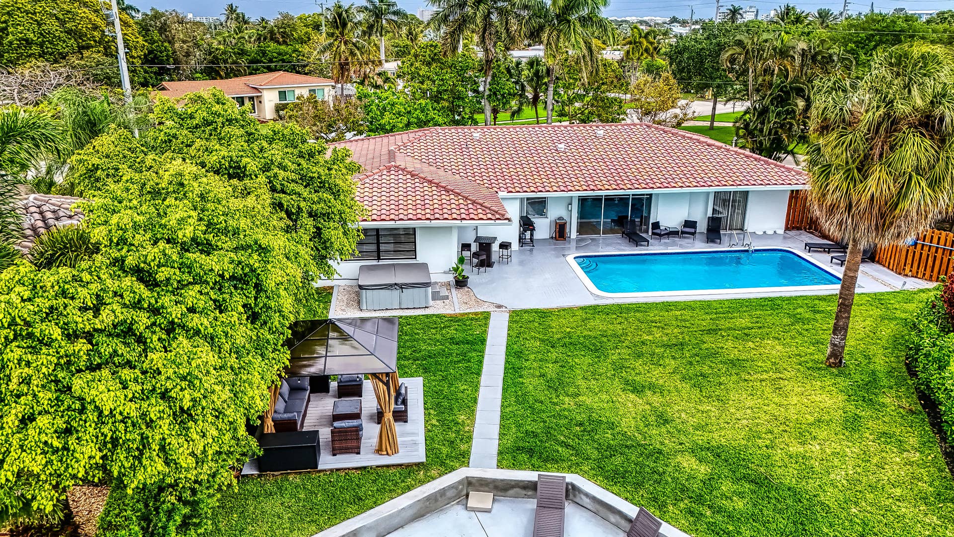 1250 SE 10TH Street, Deerfield Beach, Deerfield Beach, FL 33441 Expansive backyard featuring a rectangular swimming pool, concrete patio, and lush green lawn