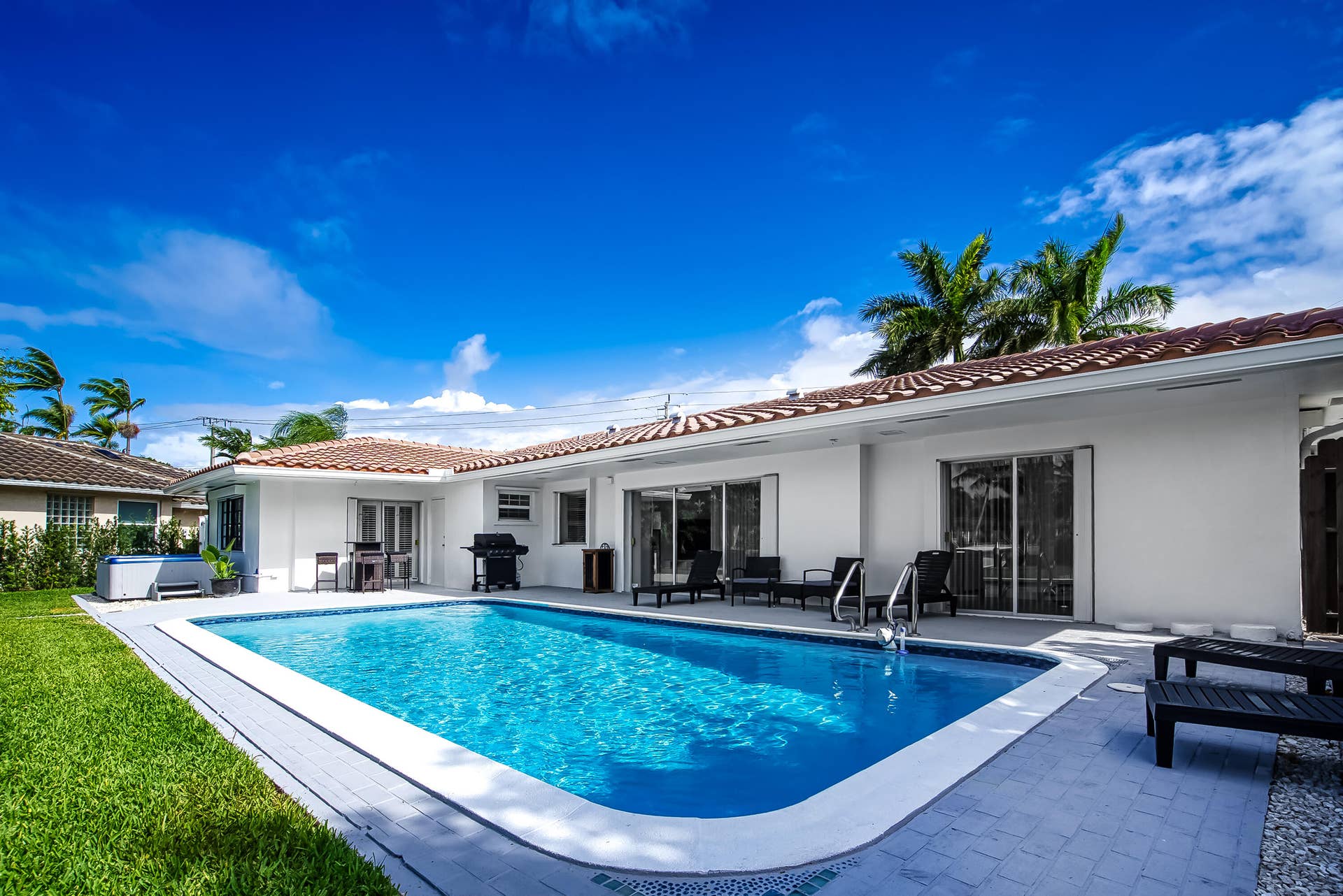 1250 SE 10TH Street, Deerfield Beach, Deerfield Beach, FL 33441 Rectangular swimming pool with light blue water and a tiled edge, surrounded by a light gray paver patio