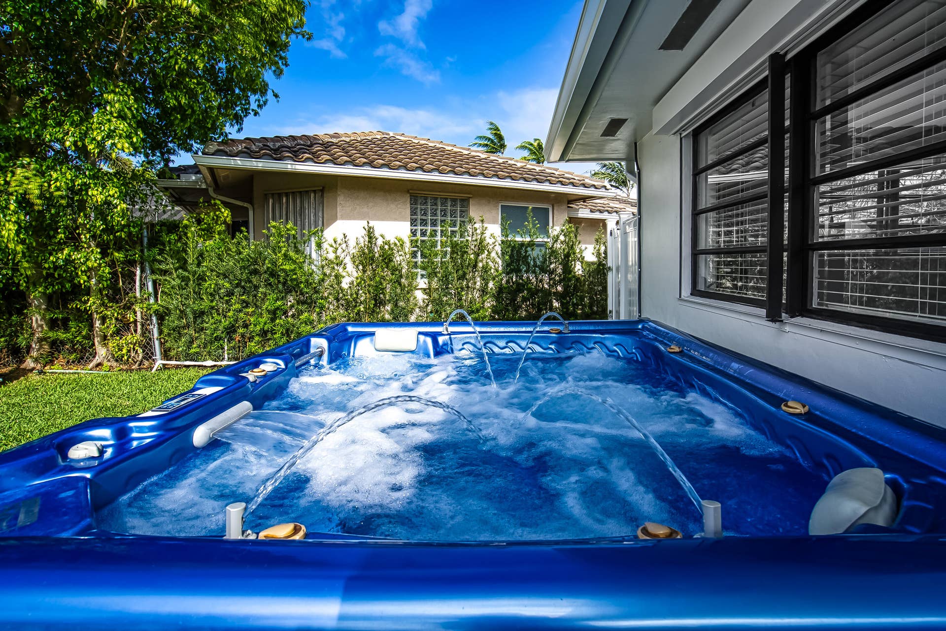 1250 SE 10TH Street, Deerfield Beach, Deerfield Beach, FL 33441 Invigorating blue spa with multiple jets, featuring a surrounding green lawn and mature landscaping