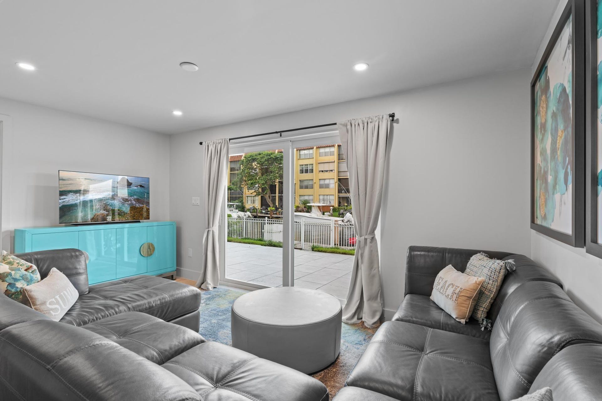 Recessed lighting illuminates this bright living space featuring a sliding glass door to an outdoor patio