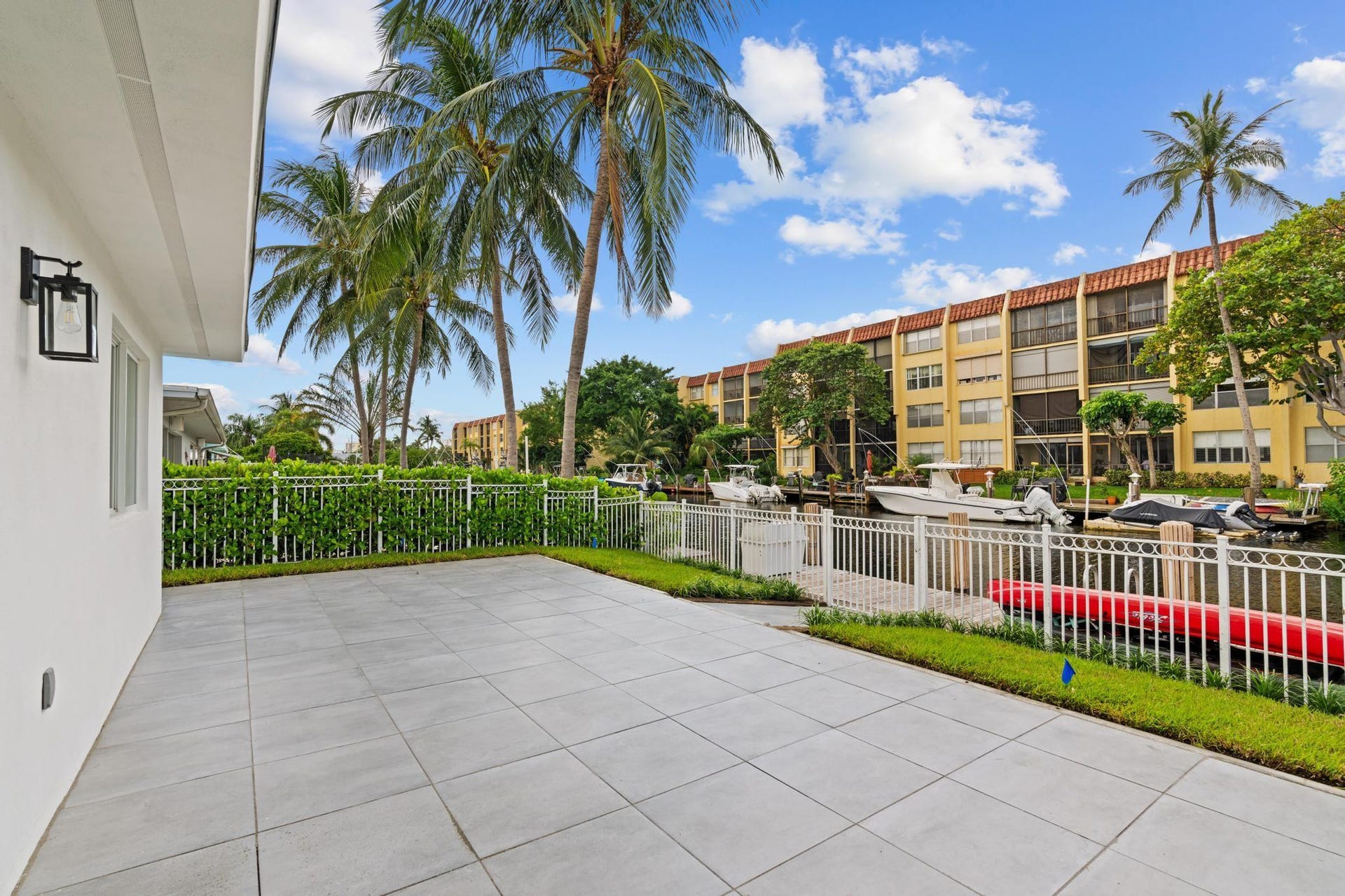 Expansive patio with large format tile, white exterior siding, and a matte black outdoor lantern