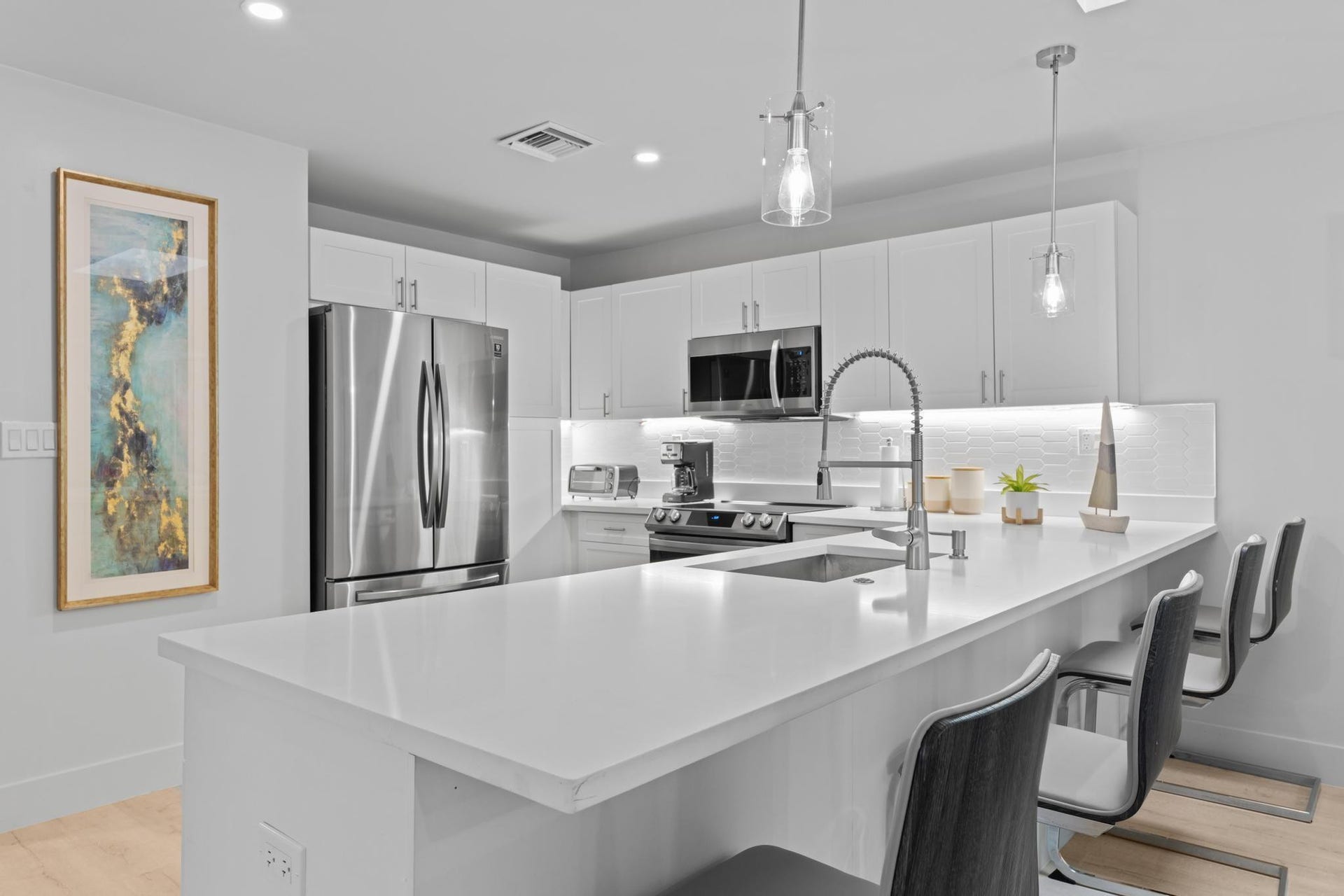 Kitchen featuring white cabinetry, stainless steel appliances, a large island with an undermount sink, and recessed lighting
