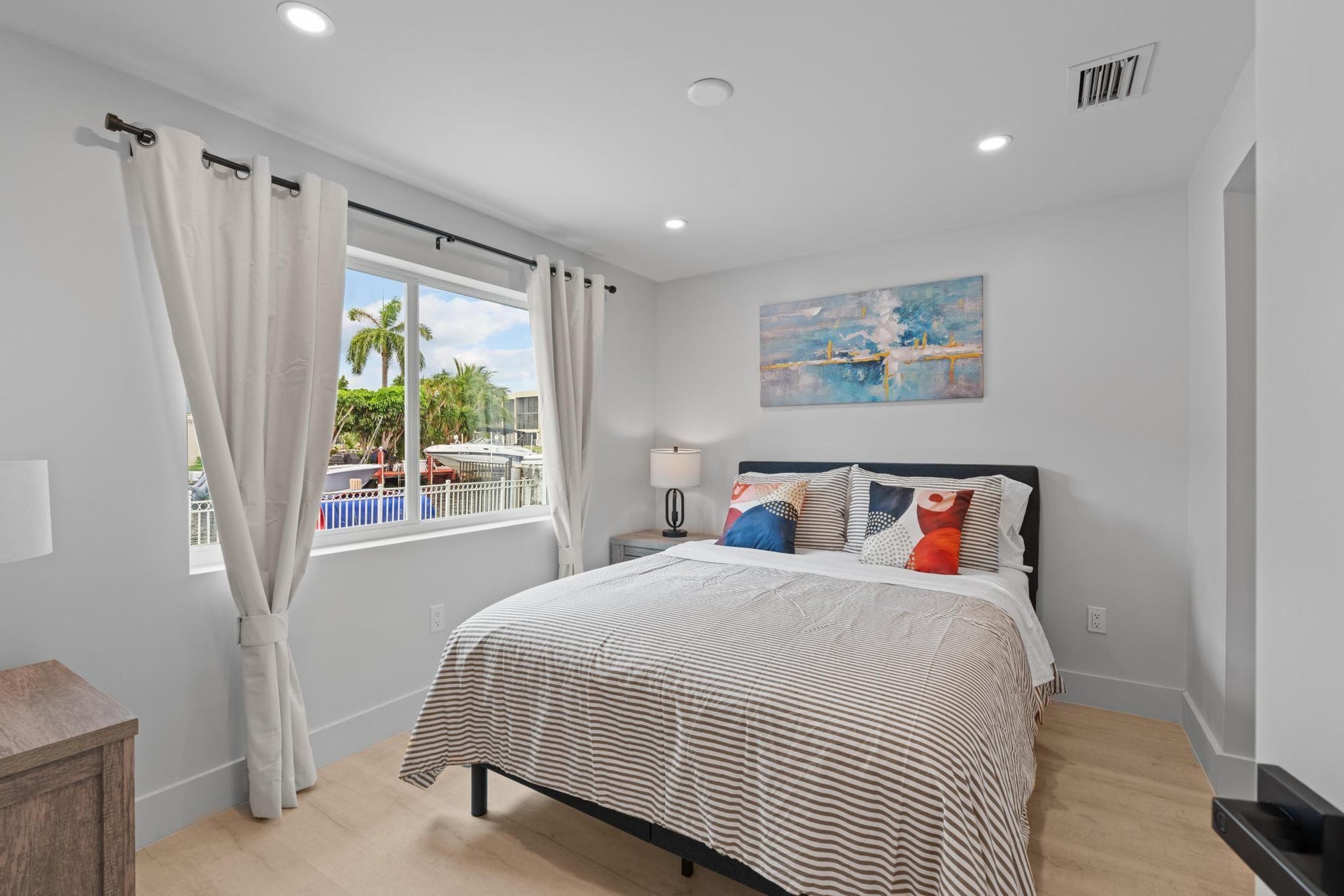 Recessed lighting, wood-finish flooring, and a large window with white casing