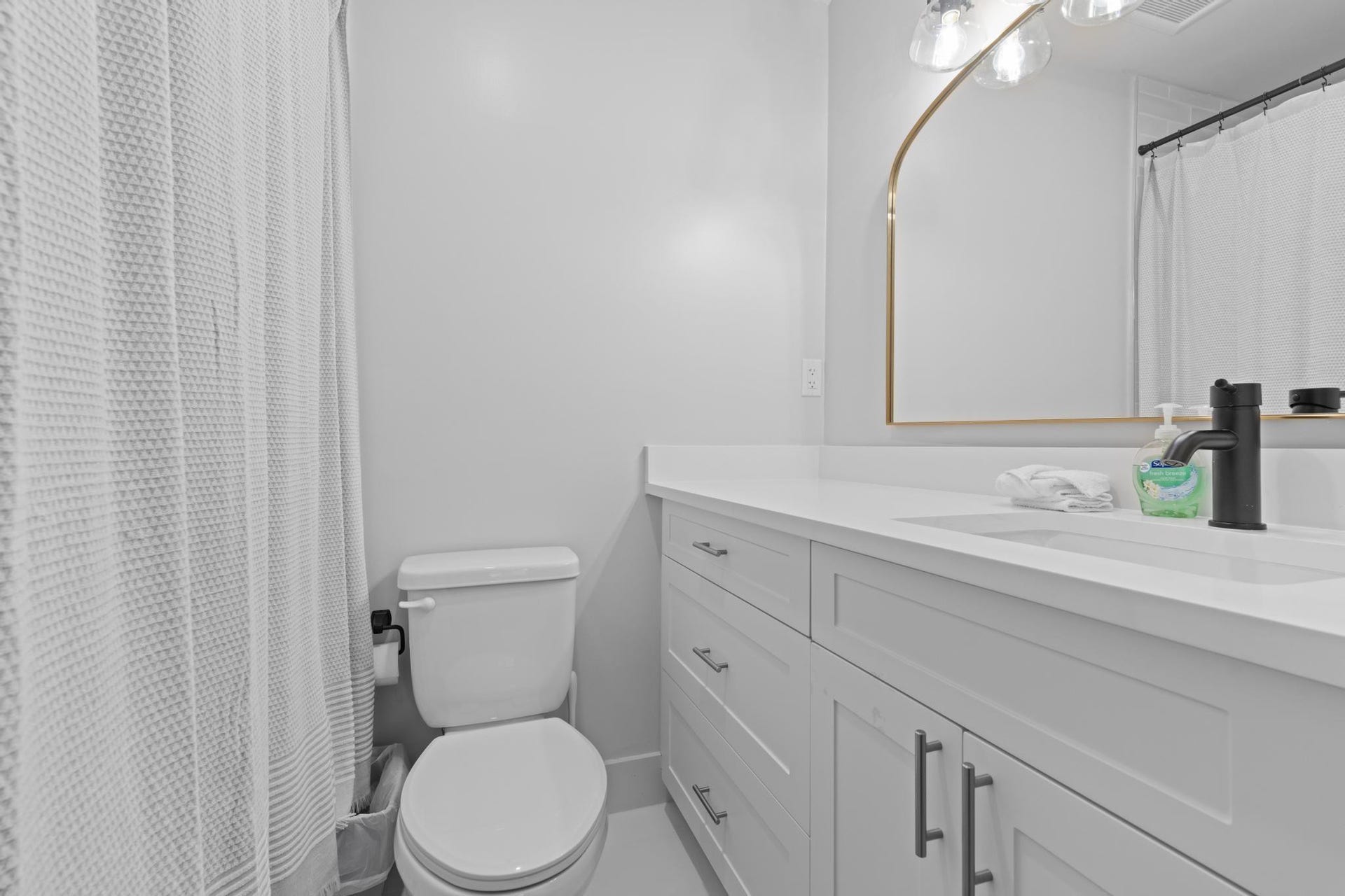White vanity with shaker-style cabinetry, a white countertop, and an undermount sink with a matte black faucet