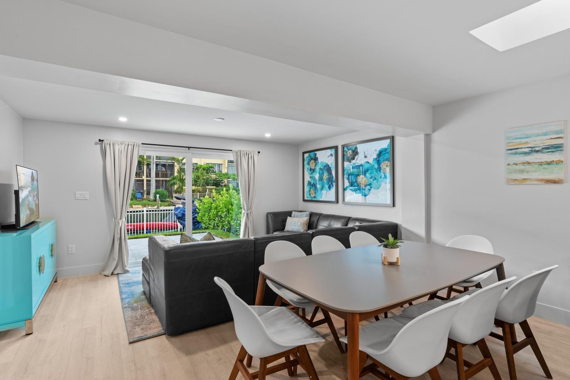 Open-concept living area with wood-finish flooring, recessed lighting, and a skylight