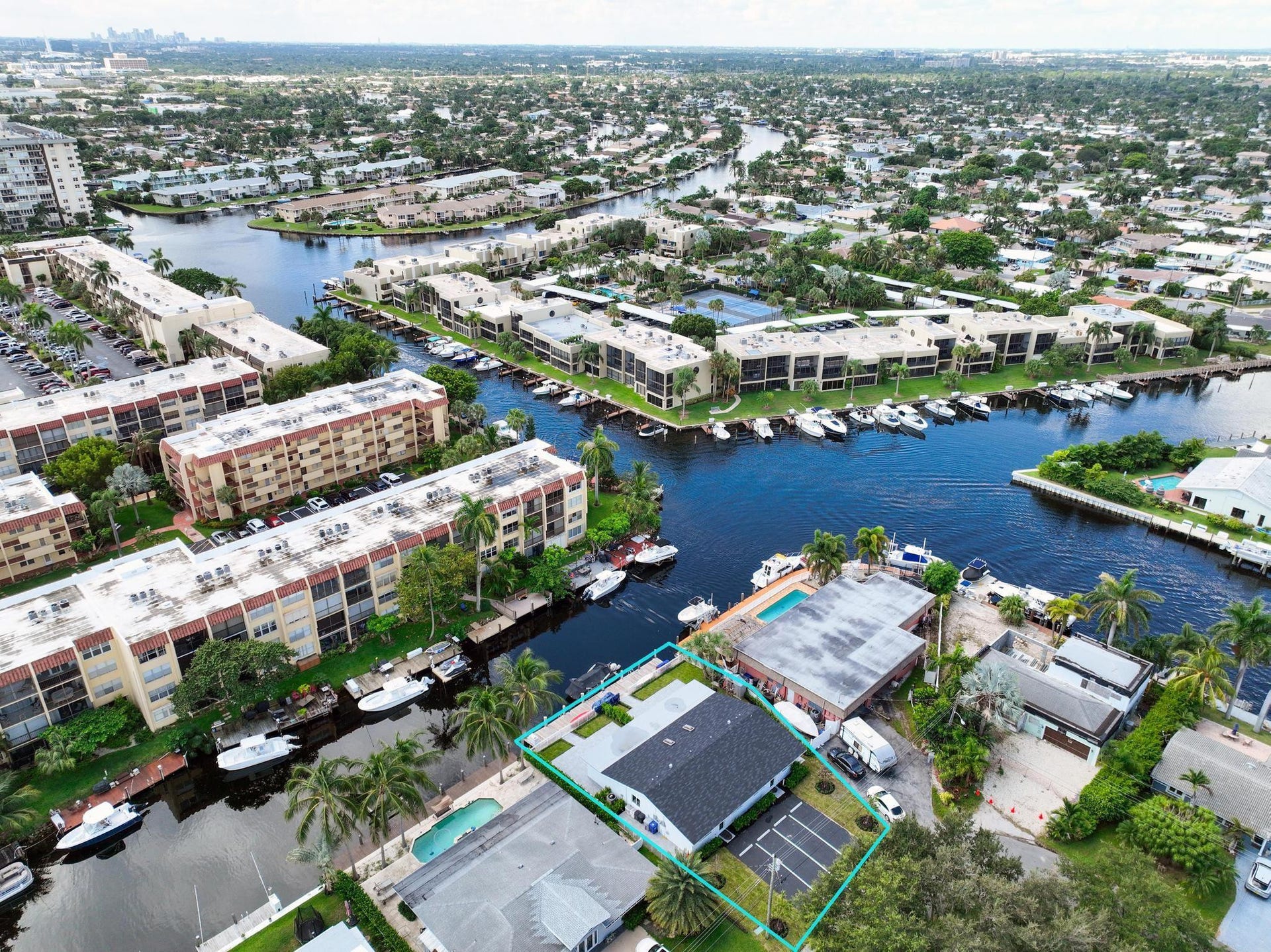 Waterfront property featuring a private boat dock, adjacent pool, and ample exterior parking