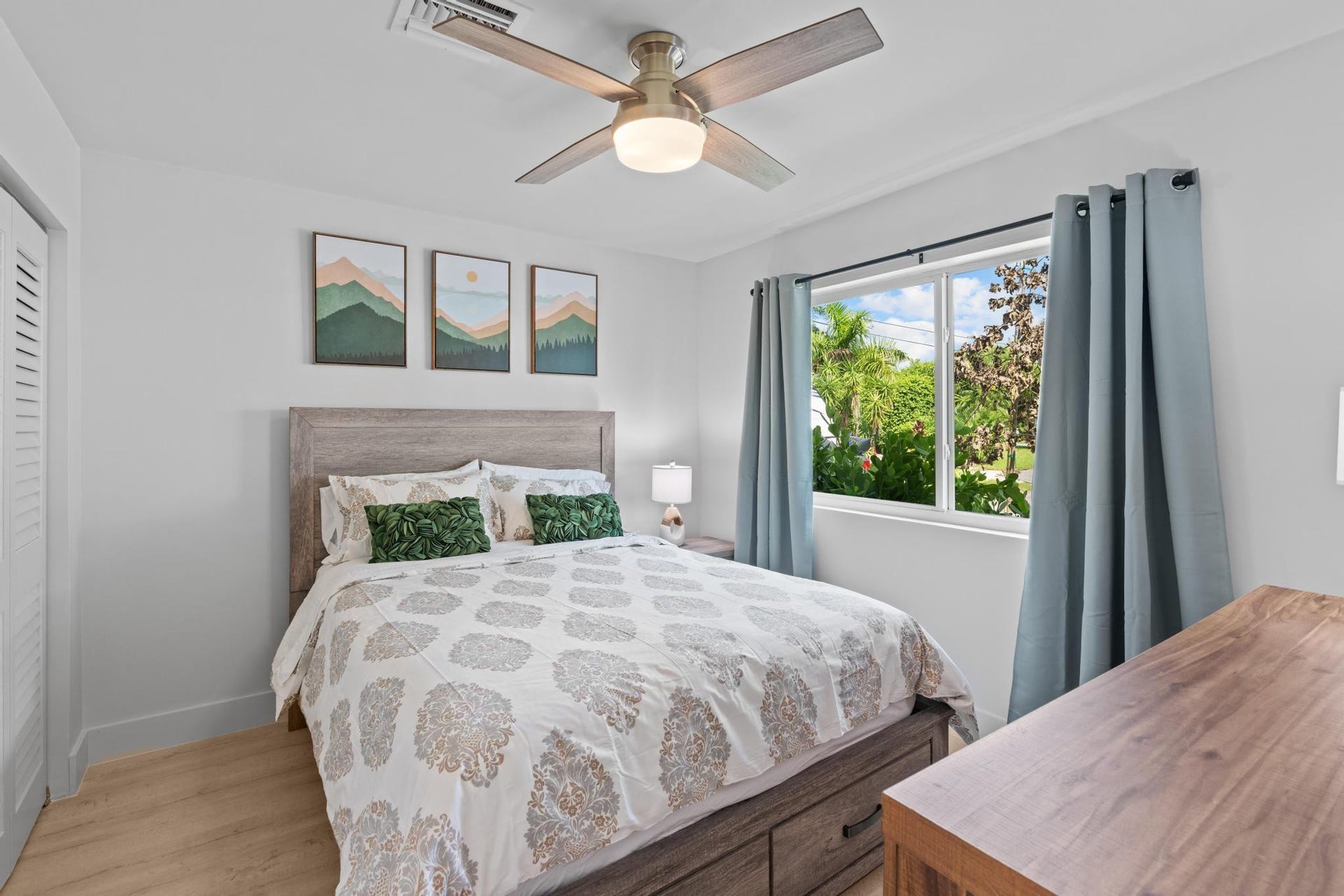 Light wood-finish flooring, a modern ceiling fan, and a louvered closet door