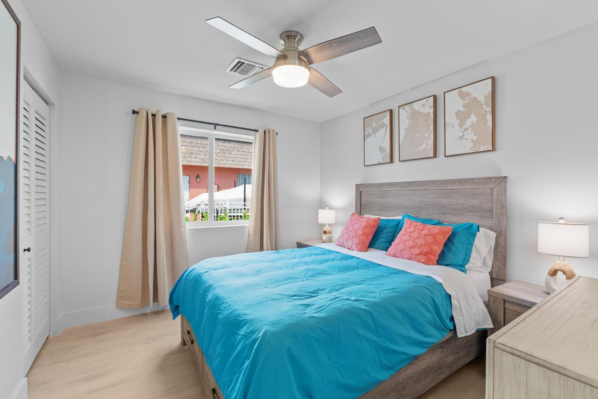 Wood-finish flooring, ceiling fan, window with curtain rods, shutter-style closet door, and a built-in headboard