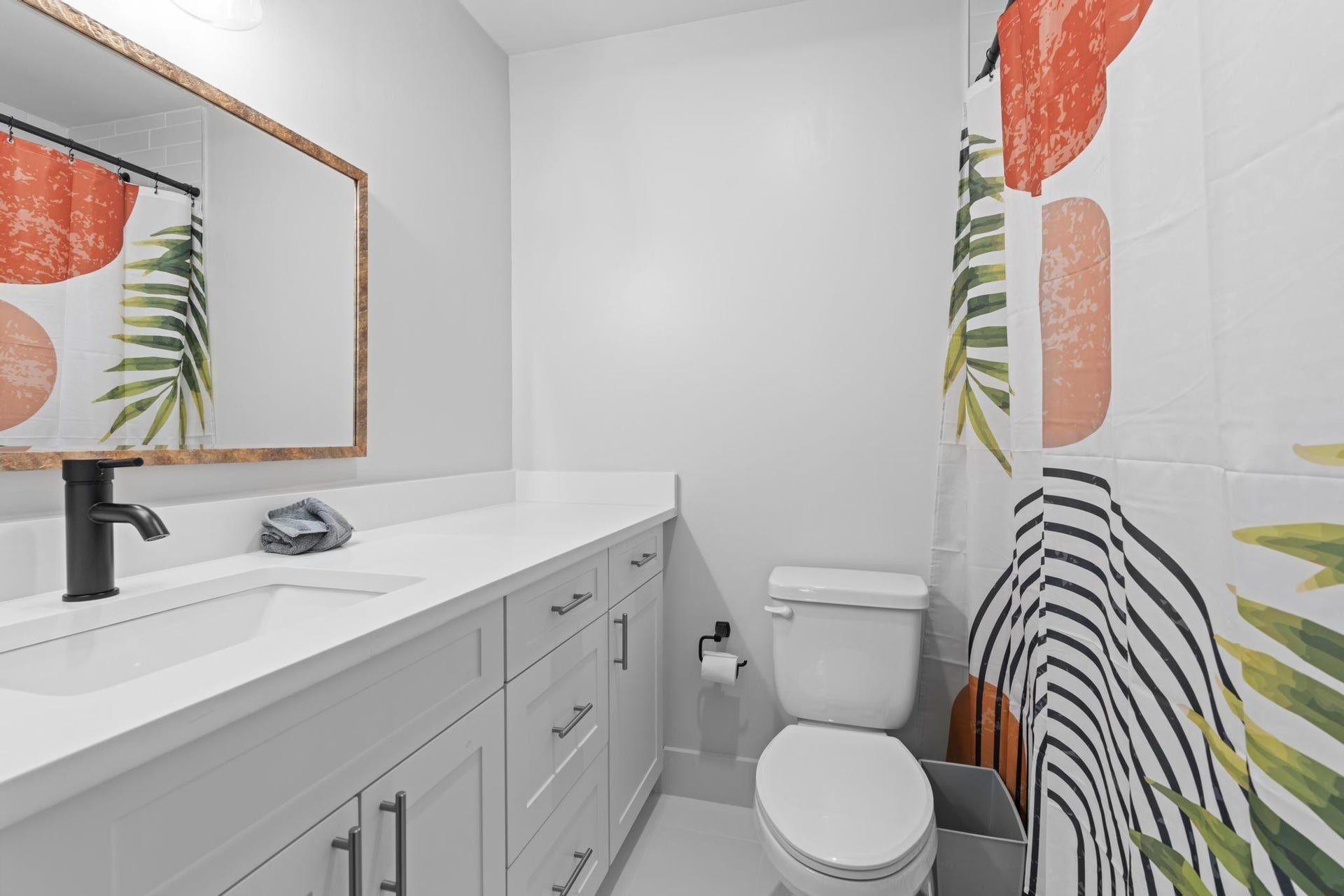 White vanity with integrated sink, matte black faucet, framed mirror, and light gray wall paint