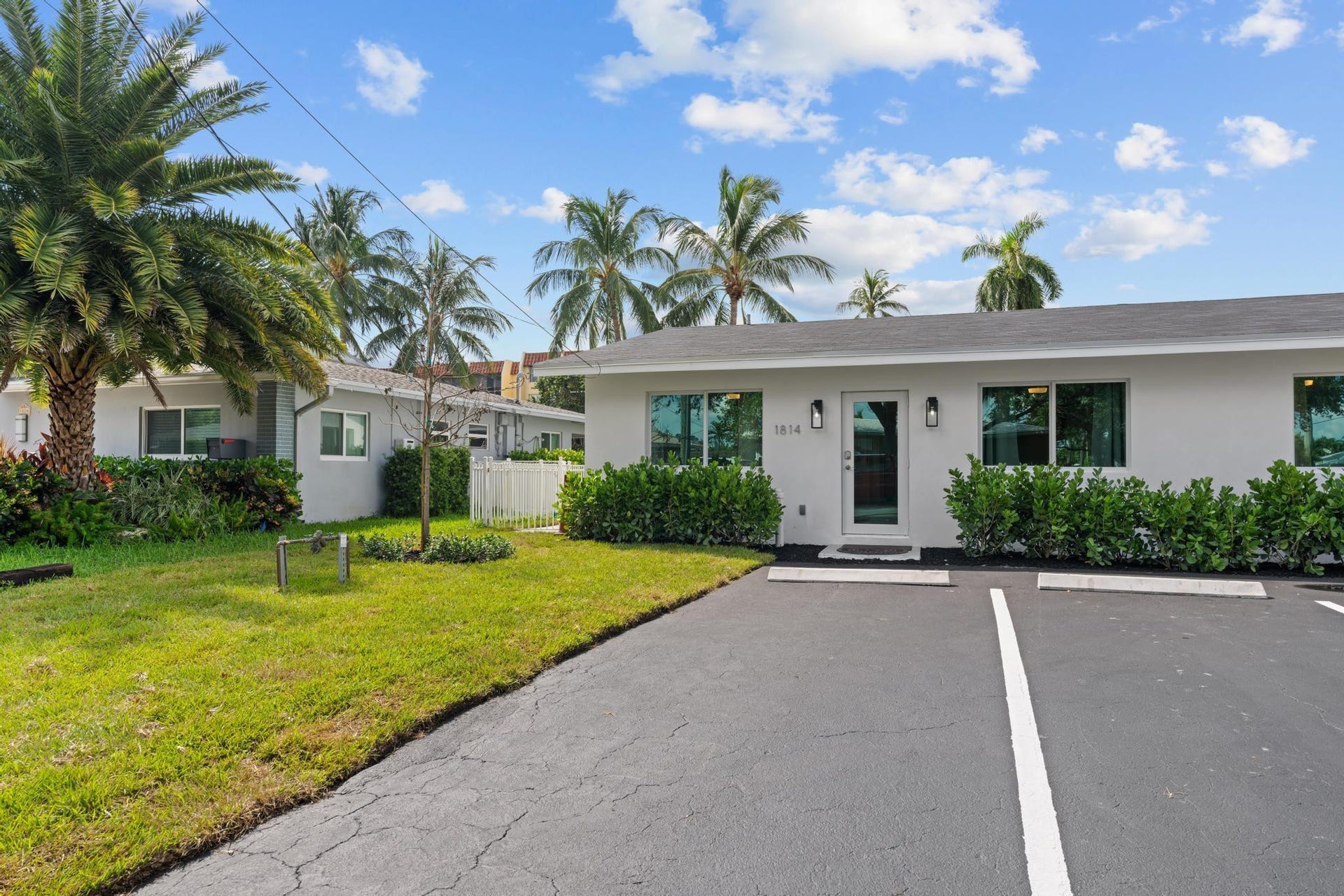 Modern exterior with expansive windows, manicured landscaping, and a convenient paved parking area