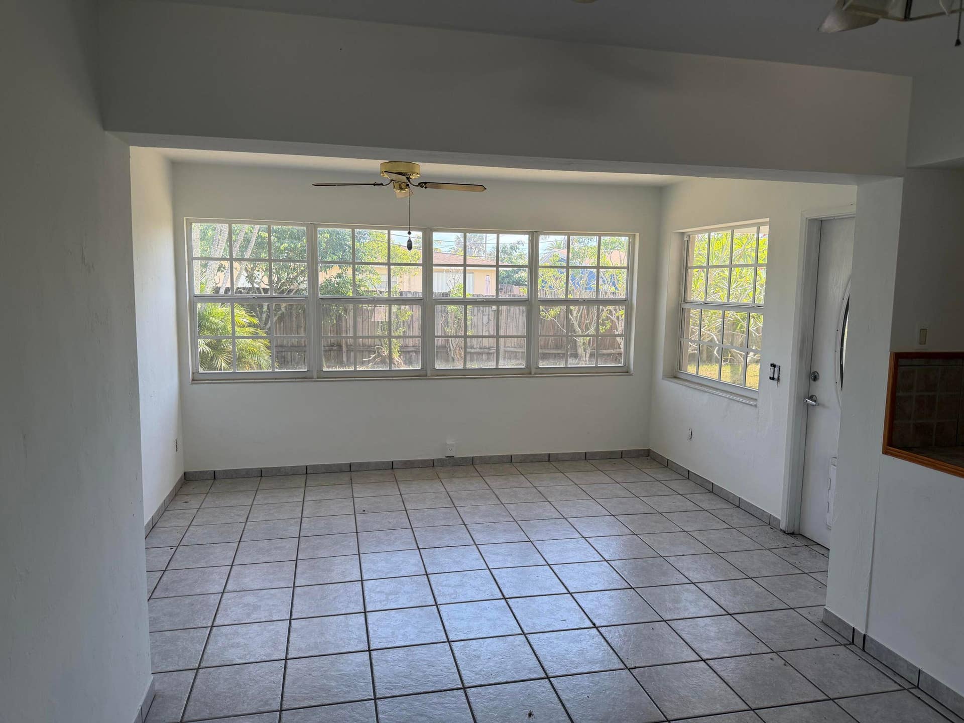 2924 NW 9TH Terrace, Wilton Manors, FL 33311 Tiled flooring, multiple windows, ceiling fan, white walls, and a perimeter fence