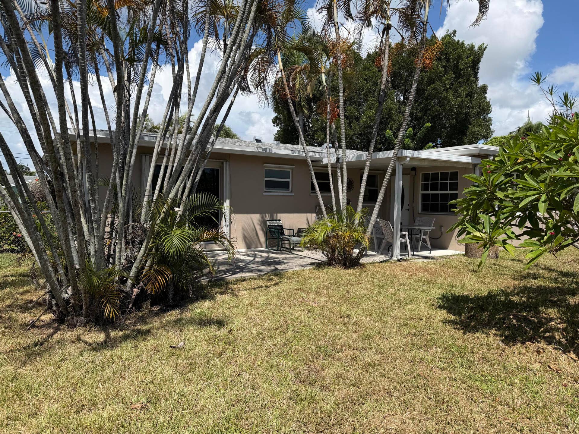 2924 NW 9TH Terrace, Wilton Manors, FL 33311 Rear exterior with a concrete patio, covered porch area, and mature palm trees