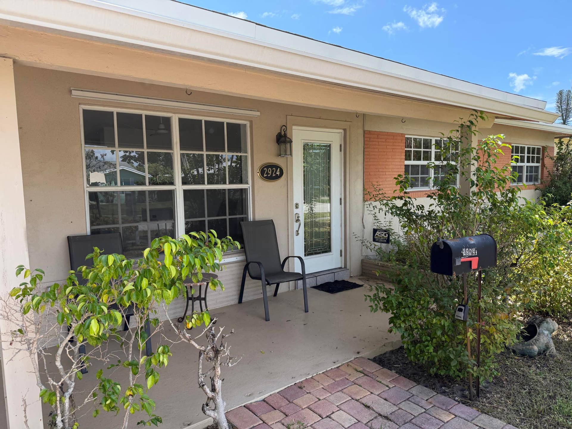2924 NW 9TH Terrace, Wilton Manors, FL 33311 Covered front porch with a paneled glass entry door, brick exterior accents, and a paver walkway