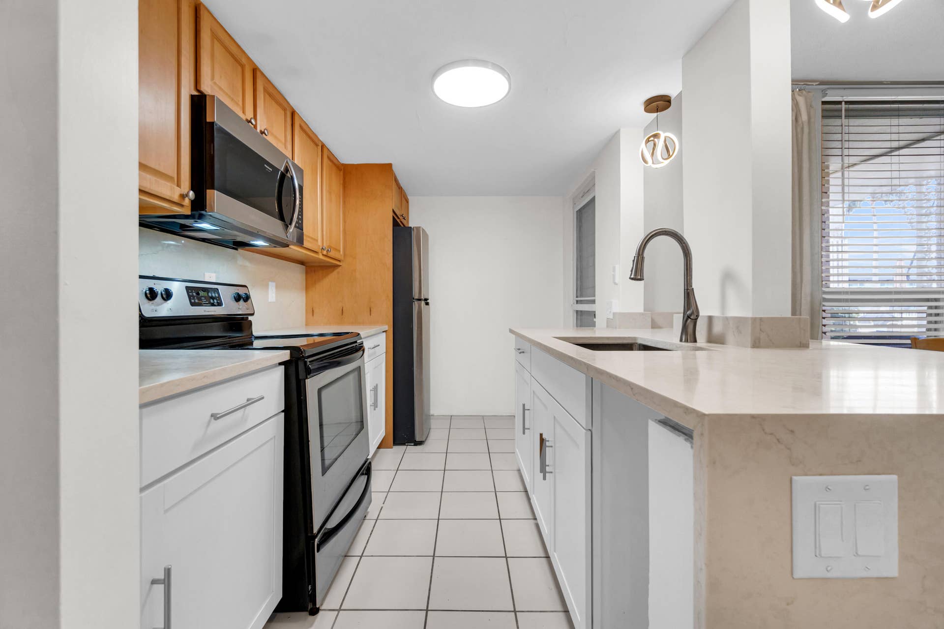 2840 NE 33RD Court, #2, Fort Lauderdale, FL 33306 Kitchen featuring stainless steel appliances, light wood-finish cabinetry, light-toned countertops, and tile flooring