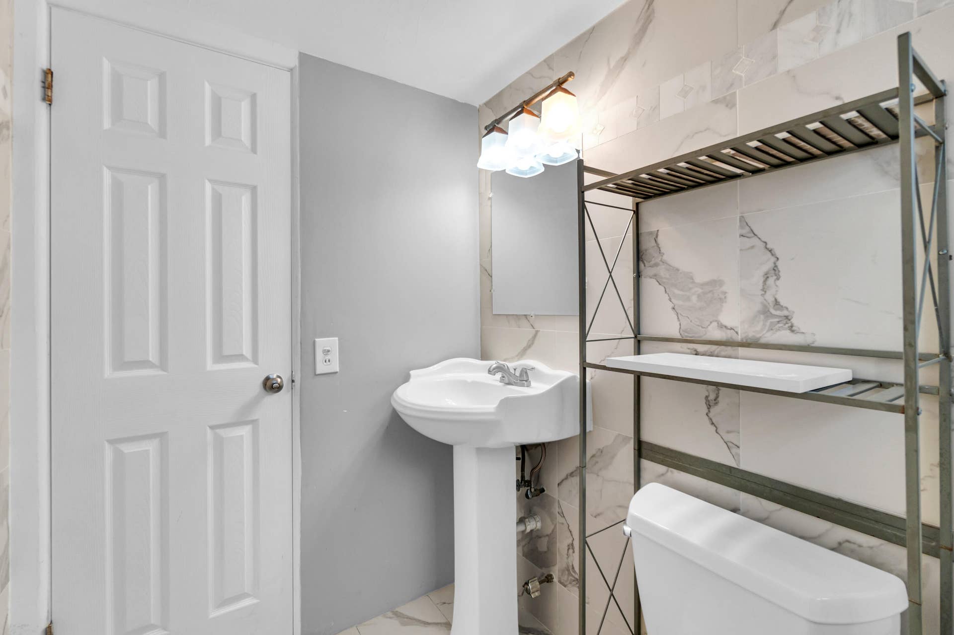 2840 NE 33RD Court, #2, Fort Lauderdale, FL 33306 Pedestal sink with chrome faucet, wall-mounted light fixture, and white panel door