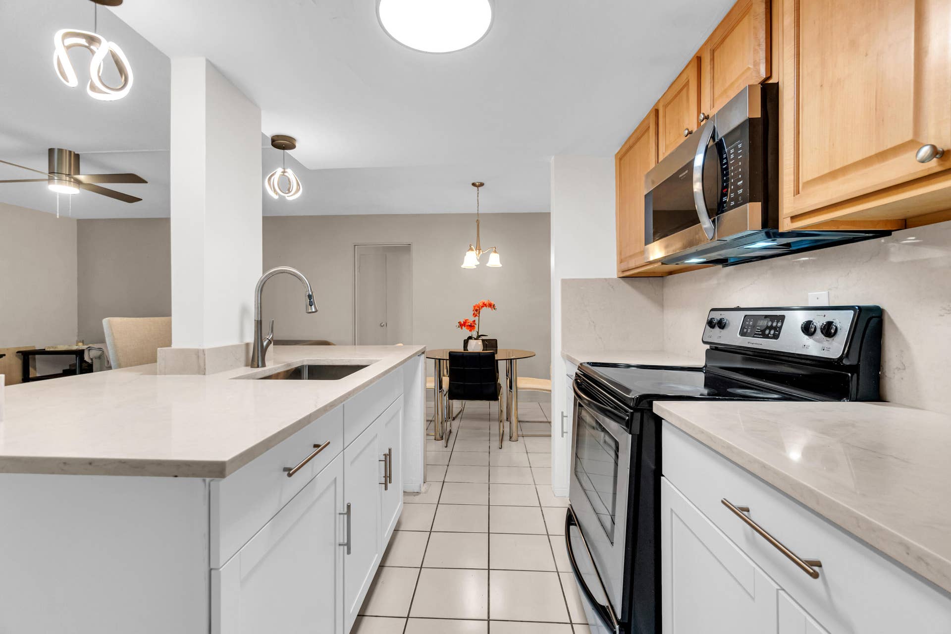 2840 NE 33RD Court, #2, Fort Lauderdale, FL 33306 Kitchen featuring an island with an undermount sink, white cabinetry, light-toned countertops, and stainless steel appliances