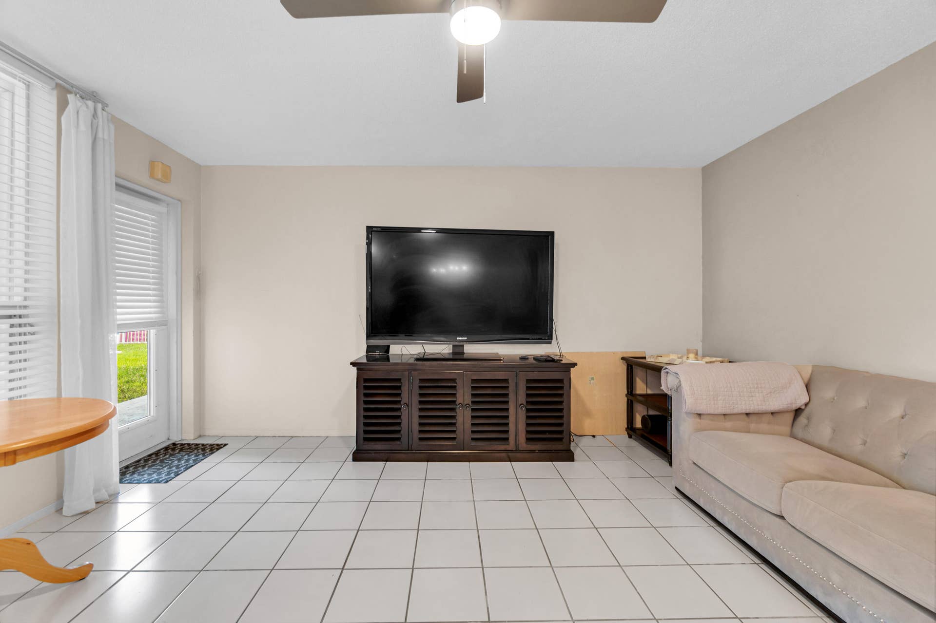 2840 NE 33RD Court, #2, Fort Lauderdale, FL 33306 Light-toned square tile flooring, ceiling fan with integrated lighting, and a glass-paneled door with horizontal blinds