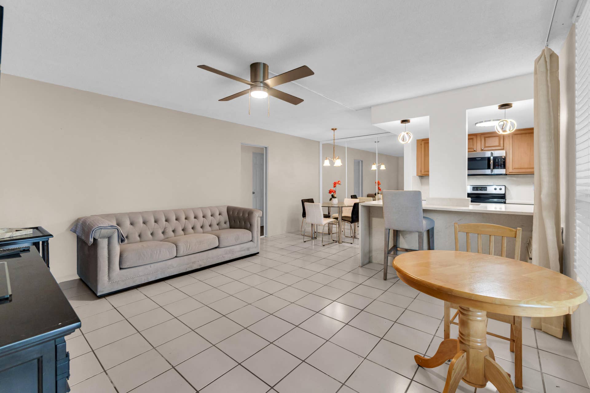 2840 NE 33RD Court, #2, Fort Lauderdale, FL 33306 Open concept living area featuring tile flooring, ceiling fan, and recessed kitchen pass-through with pendant lighting