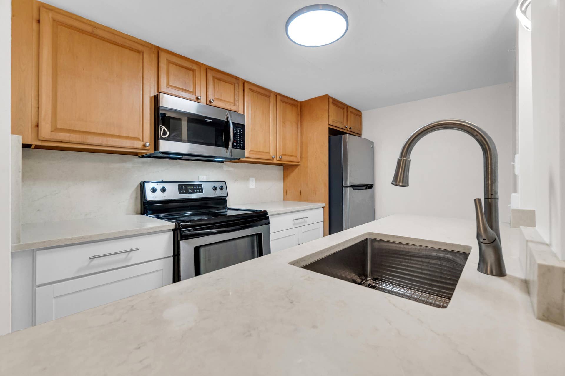 2840 NE 33RD Court, #2, Fort Lauderdale, FL 33306 Kitchen featuring stainless steel appliances, light wood-finish cabinetry, light-toned countertops, and a single-basin sink with a gooseneck faucet