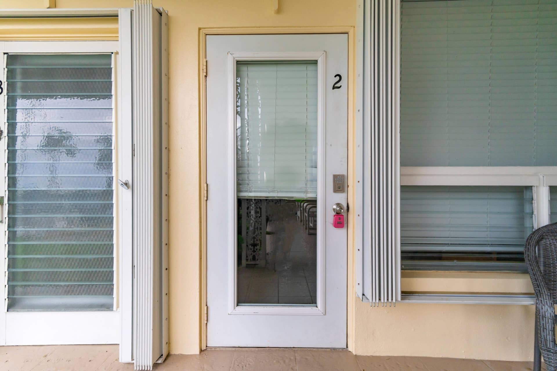 2840 NE 33RD Court, #2, Fort Lauderdale, FL 33306 Entry door with glass panel, adjacent jalousie window, and exterior accordion shutters