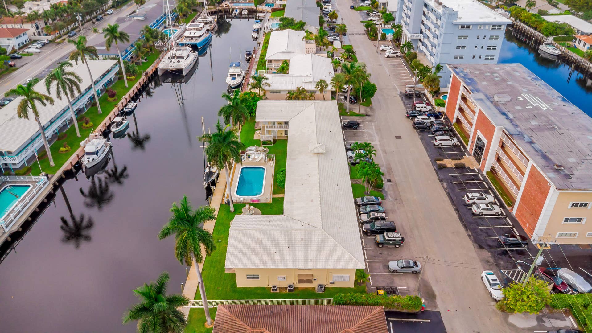 2840 NE 33RD Court, #2, Fort Lauderdale, FL 33306 Waterfront property featuring a canal, mature palm trees, an outdoor swimming pool, and dedicated parking