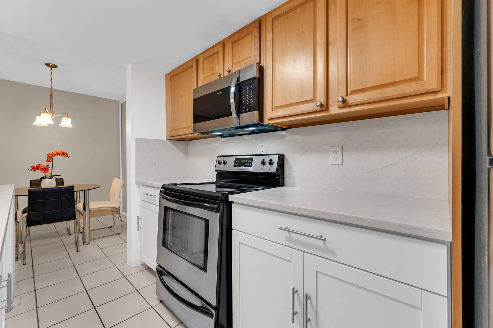 2840 NE 33RD Court, #2, Fort Lauderdale, FL 33306 Kitchen featuring stainless steel appliances, light wood-finish upper cabinetry, white lower cabinetry, and light-toned countertops with a matching backsplash