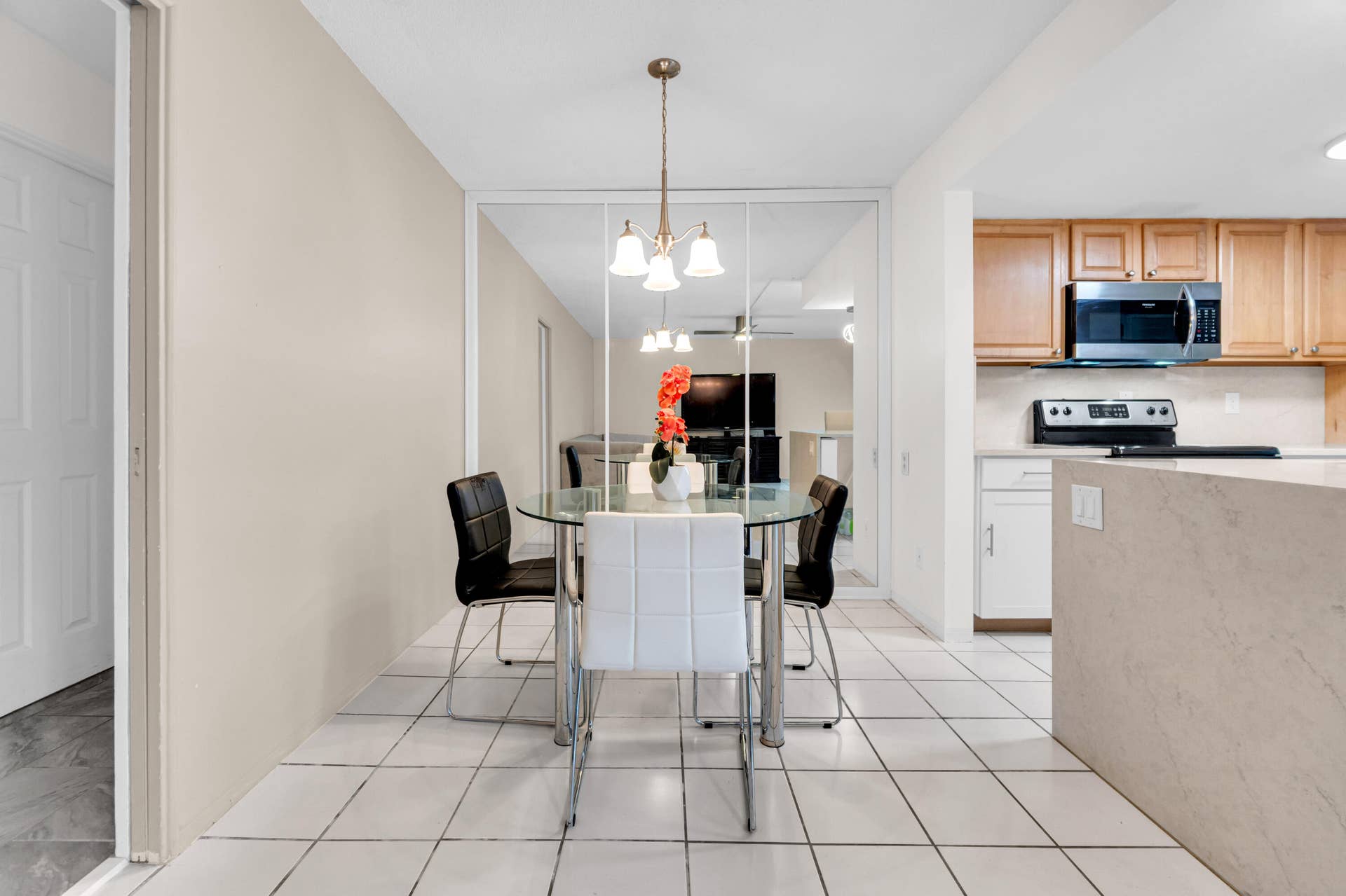 2840 NE 33RD Court, #2, Fort Lauderdale, FL 33306 Tiled flooring with a warm-toned wall finish, mirrored wall panels, and a kitchen featuring wood-finish cabinetry and a built-in microwave