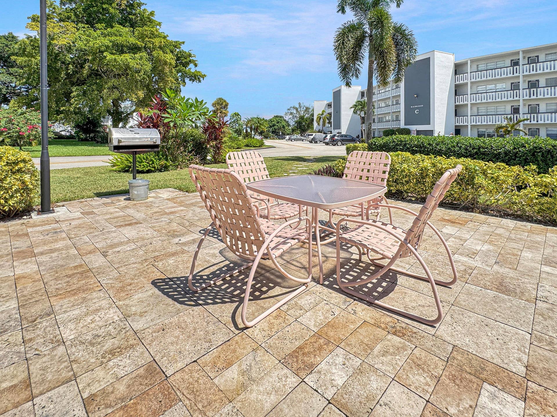 1013 HARWOOD C, #1013, Deerfield Beach, FL 33442 Paver patio surface, integrated outdoor grill, mature landscaping, well-maintained lawn, and multi-story building exterior