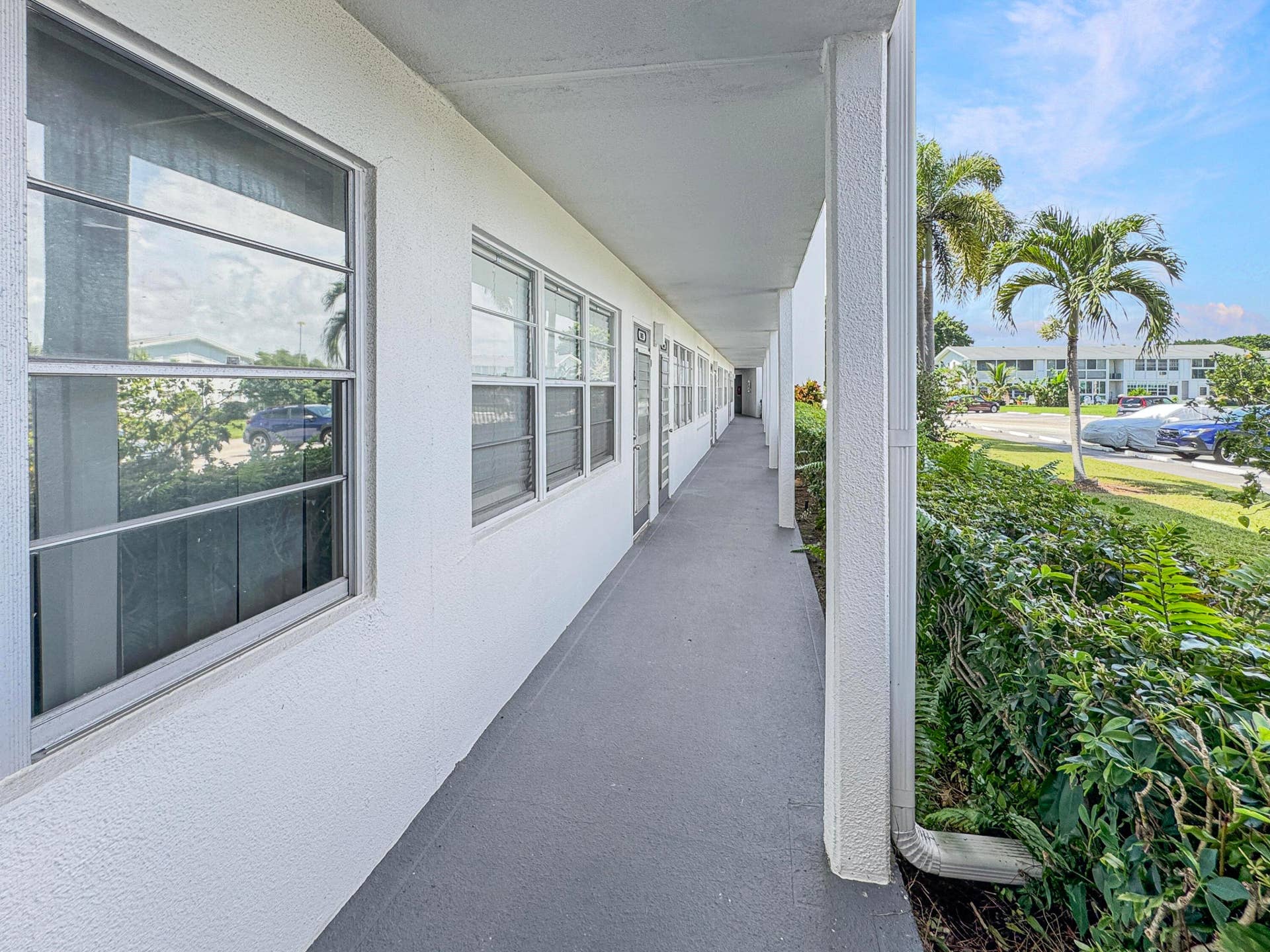 1013 HARWOOD C, #1013, Deerfield Beach, FL 33442 Covered exterior walkway featuring a textured ceiling, smooth flooring, and multiple windows
