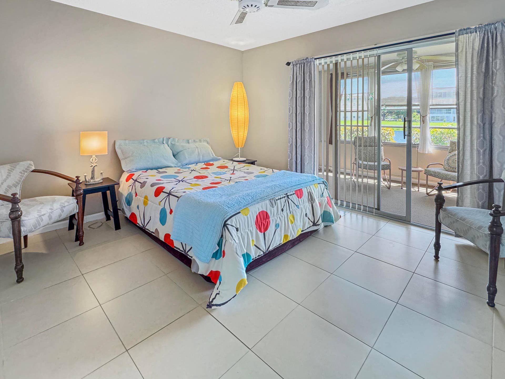 1013 HARWOOD C, #1013, Deerfield Beach, FL 33442 Light-toned tile flooring, ceiling fan, and sliding glass doors leading to a screened-in patio