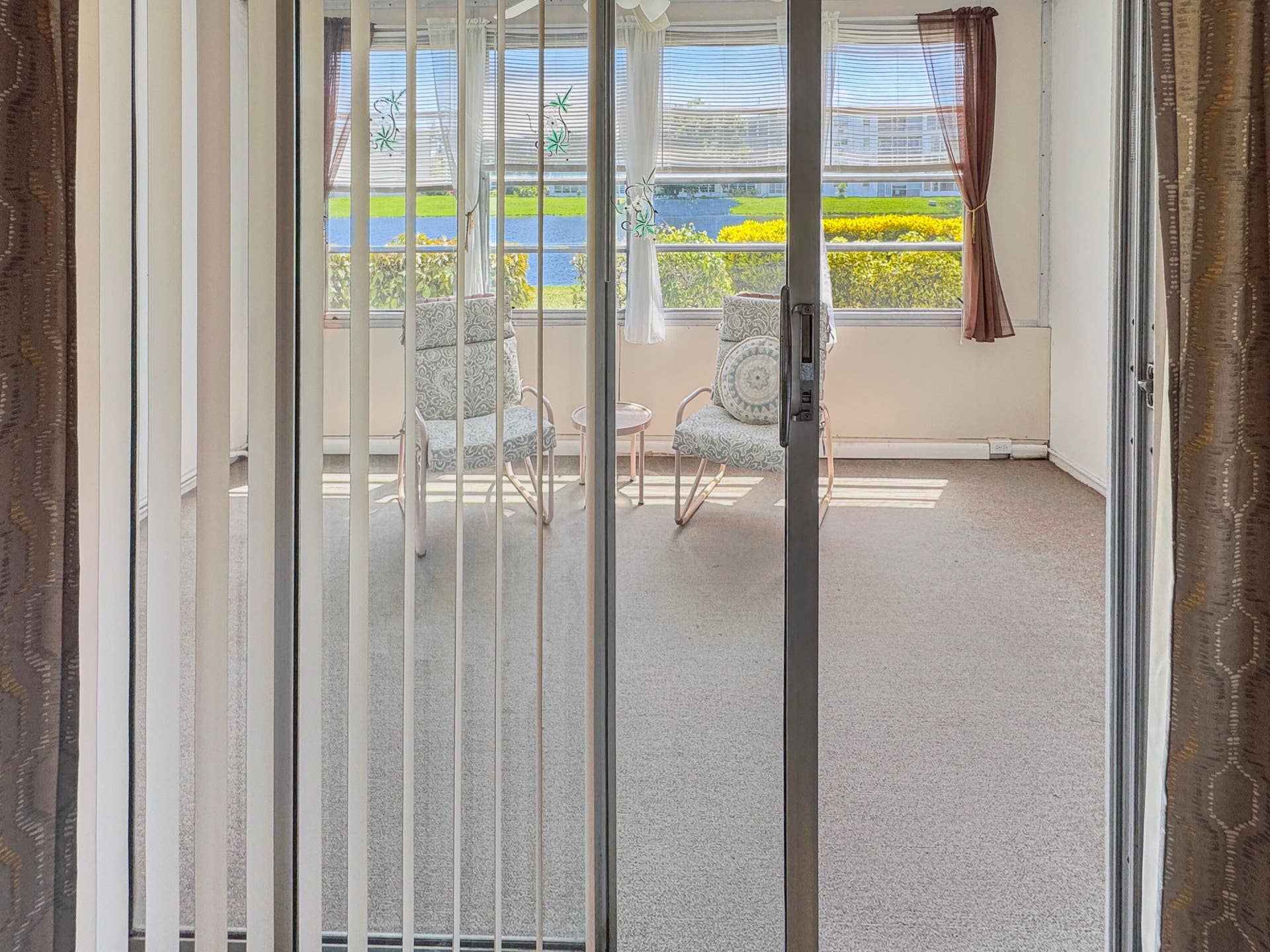 1013 HARWOOD C, #1013, Deerfield Beach, FL 33442 Sliding glass door entry to a sunroom featuring multiple windows and neutral flooring