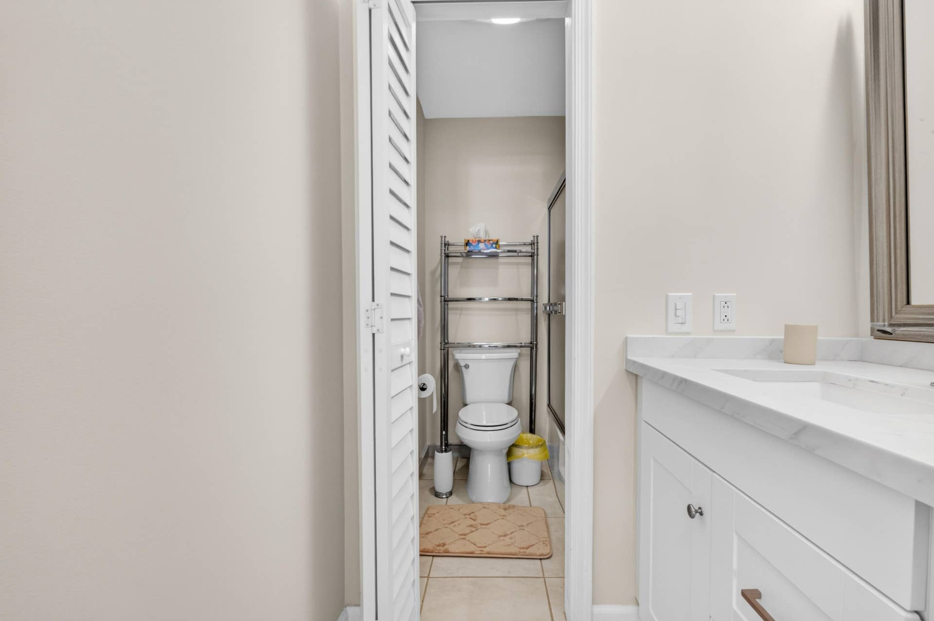 6359 Bay Club Drive, #2, Fort Lauderdale, FL 33308 Efficient bathroom layout featuring a marble-topped vanity with integrated sink, white cabinetry, and a separate water closet with tile flooring