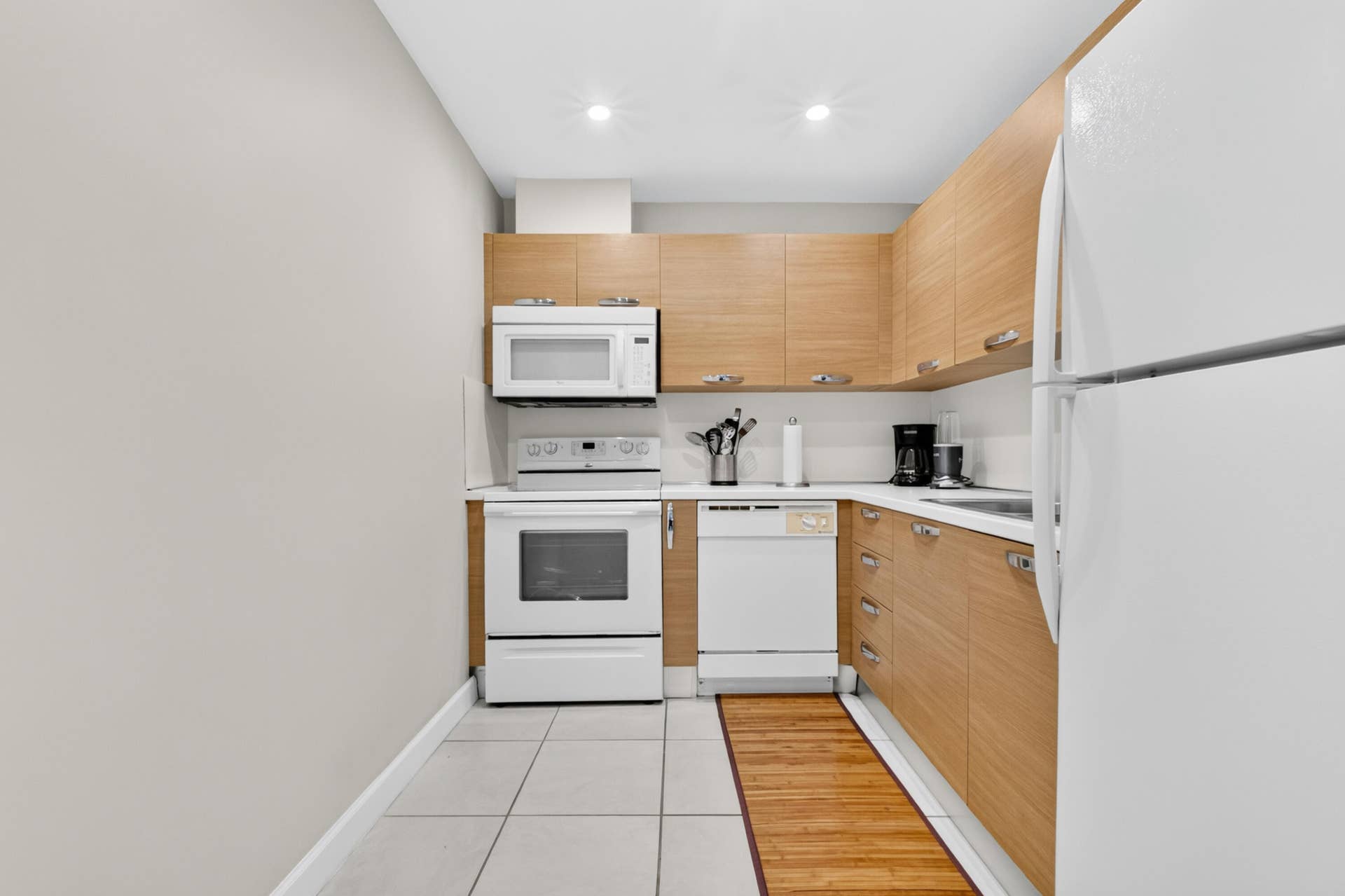 6359 Bay Club Drive, #2, Fort Lauderdale, FL 33308 Galley kitchen featuring natural wood-finish cabinetry, white appliances including a gas range and dishwasher, tile flooring, and recessed ceiling lighting