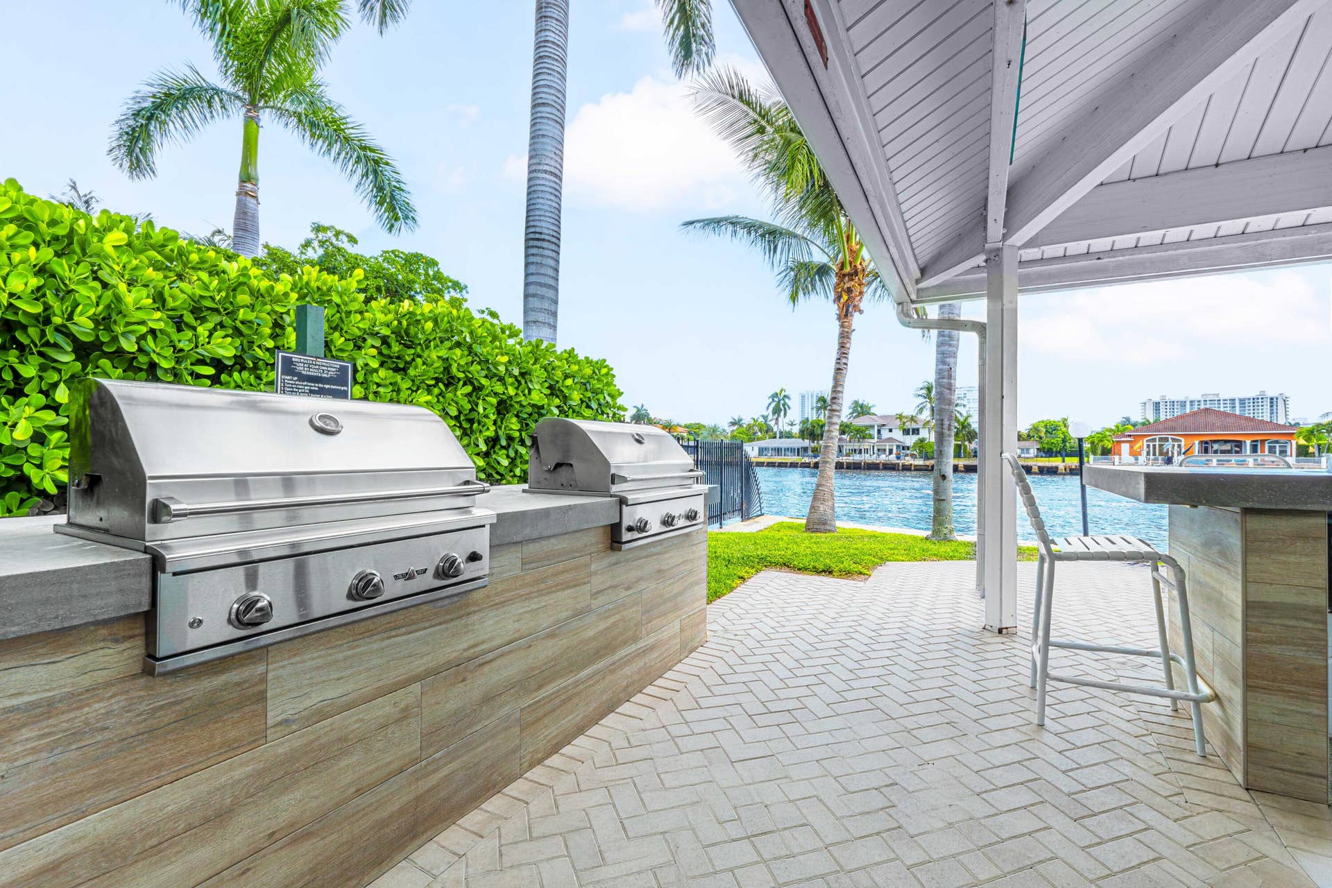 6359 Bay Club Drive, #2, Fort Lauderdale, FL 33308 Outdoor kitchen with dual stainless steel grills, a built-in bar, and a covered patio area with herringbone paver flooring