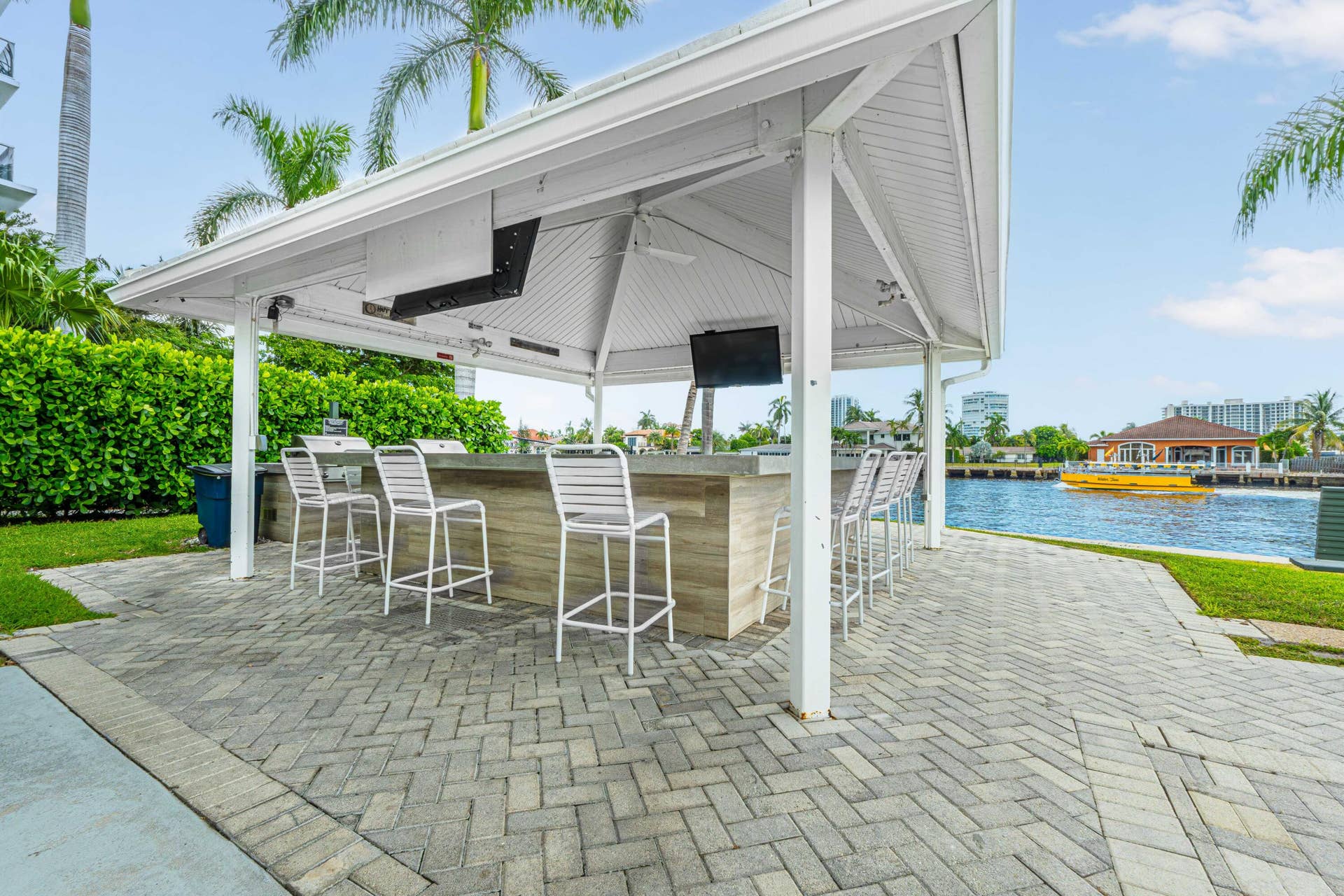 6359 Bay Club Drive, #2, Fort Lauderdale, FL 33308 Waterfront covered outdoor bar with built-in appliances, herringbone paver patio, and lush landscaping