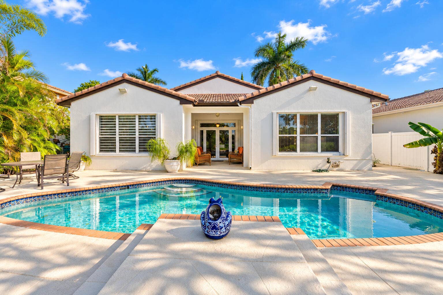 Rear exterior showcases the homes covered patio, expansive pool deck and direct connection to the outdoor living area.