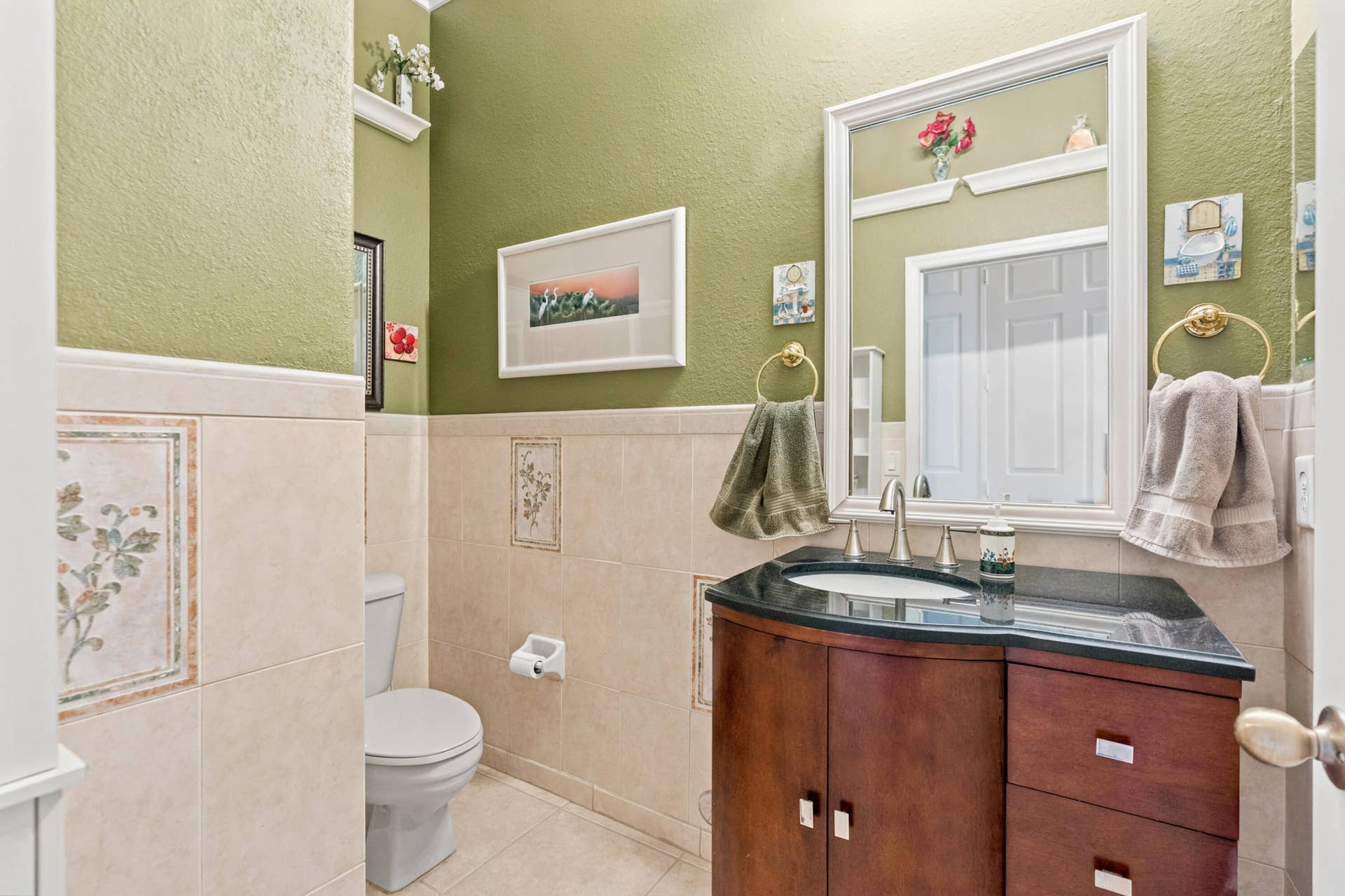Half bathroom features a granite countertop vanity, tiled walls and warm finishes.