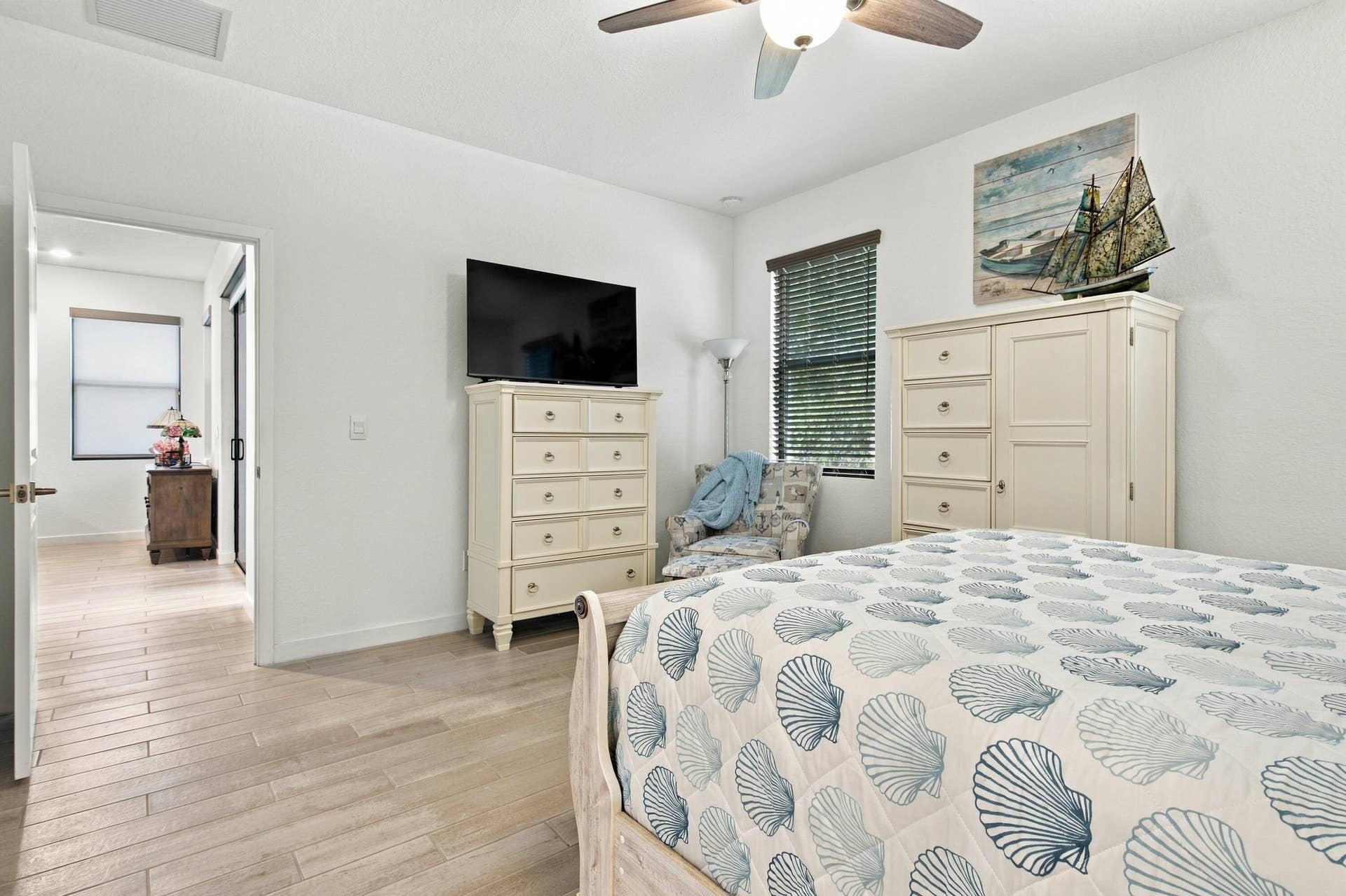 Primary bedroom with customed blinds, luxury ceramic wood like flooring, ceiling fan.