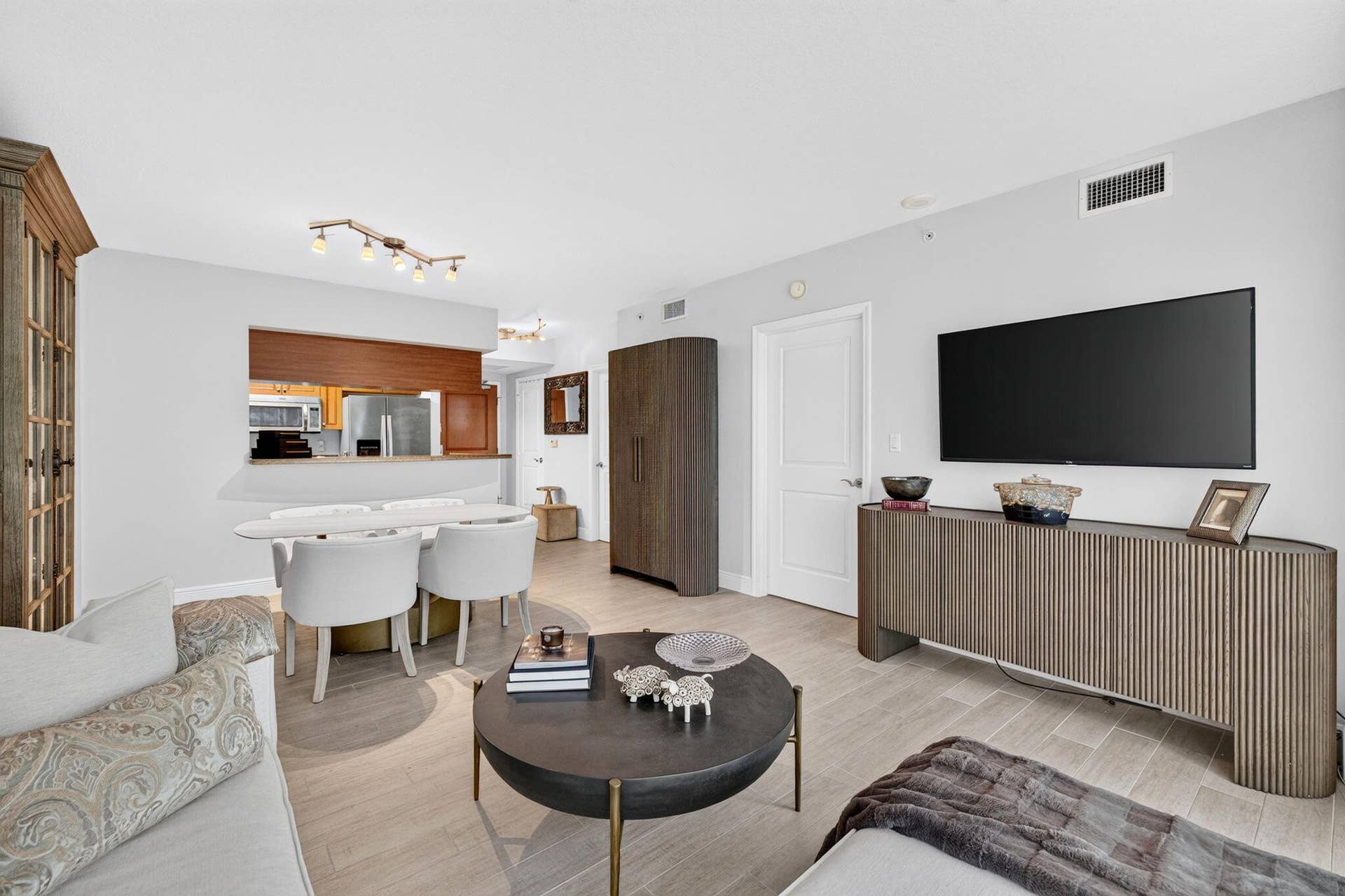 Open-concept living area with light-toned Tile flooring, recessed lighting, and a kitchen pass-through