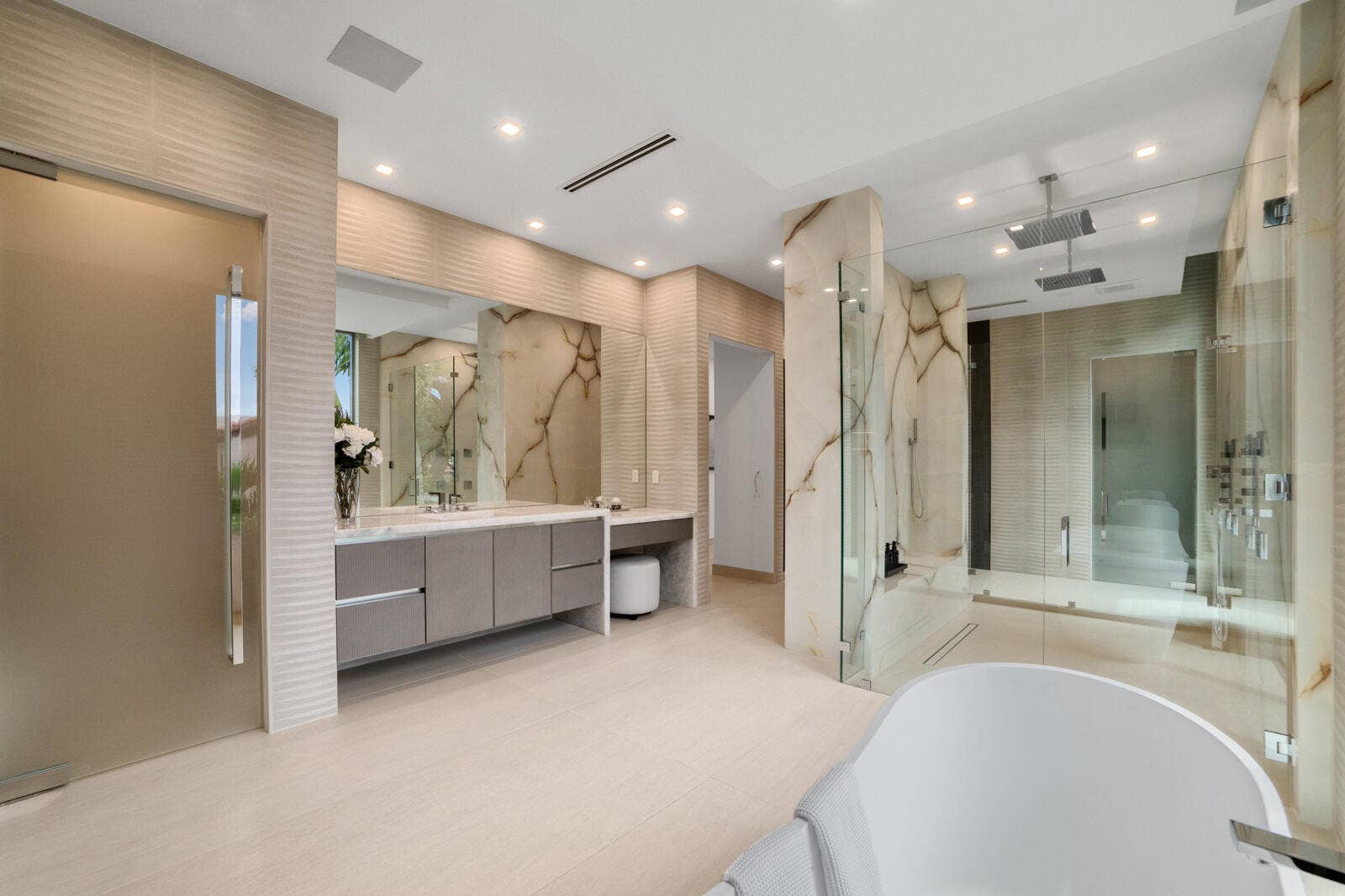 414 ROYAL PLAZA Drive, Fort Lauderdale, FL 33301 Luxurious primary bath showcasing an oversized glass-enclosed shower with dual rain heads, book-matched stone, floating vanities, and a dedicated makeup station.