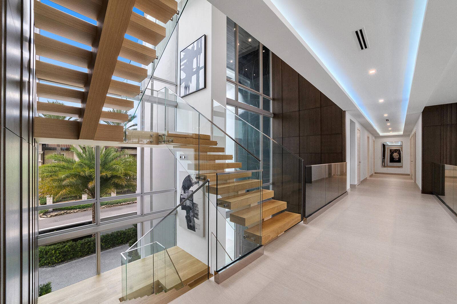 414 ROYAL PLAZA Drive, Fort Lauderdale, FL 33301 Second-floor landing showcasing the floating staircase from both sides, framed by soaring windows, glass railings, and rich wood-paneled accent walls.