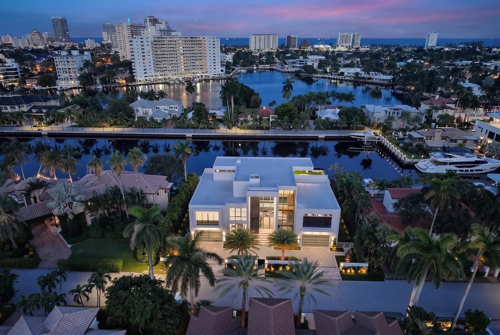 414 ROYAL PLAZA Drive, Fort Lauderdale, FL 33301 A breathtaking twilight aerial showcases the residences illuminated modern architecture, tropical landscaping, and exceptional waterfront setting, framed by serene waterways, luxury yachts, city lights, and the ocean beyond.