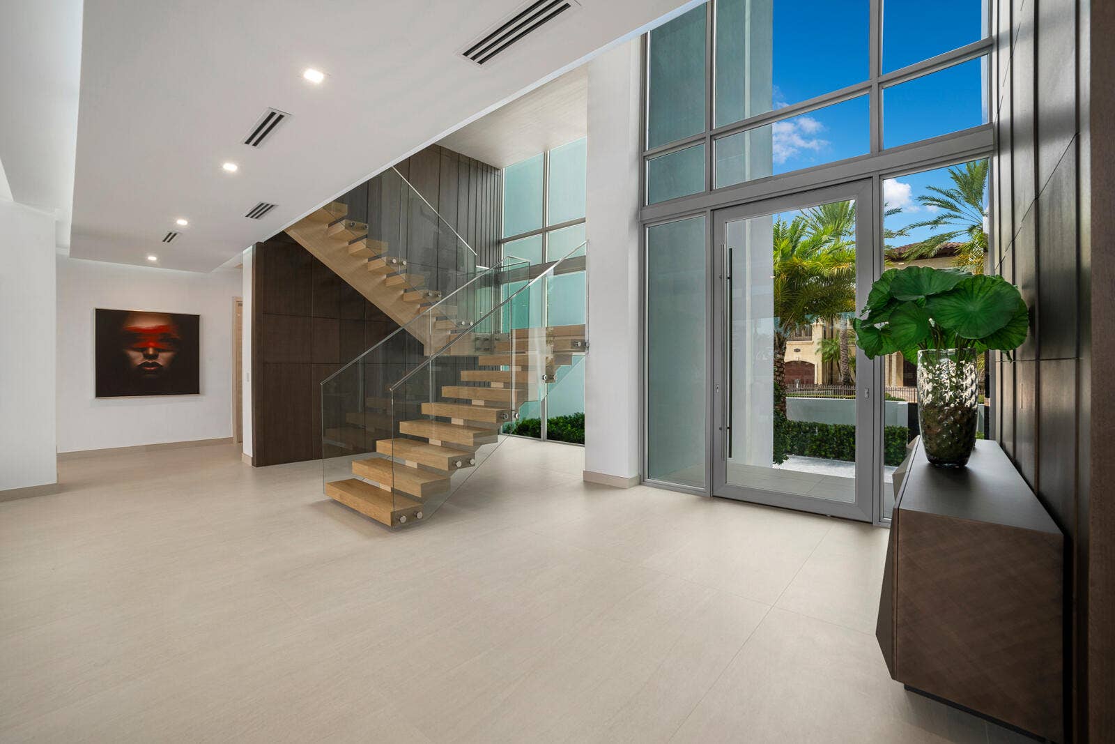 414 ROYAL PLAZA Drive, Fort Lauderdale, FL 33301 Dramatic first-floor entry showcasing soaring ceilings, a striking wood-paneled feature wall, and a floating staircase with glass railings.
